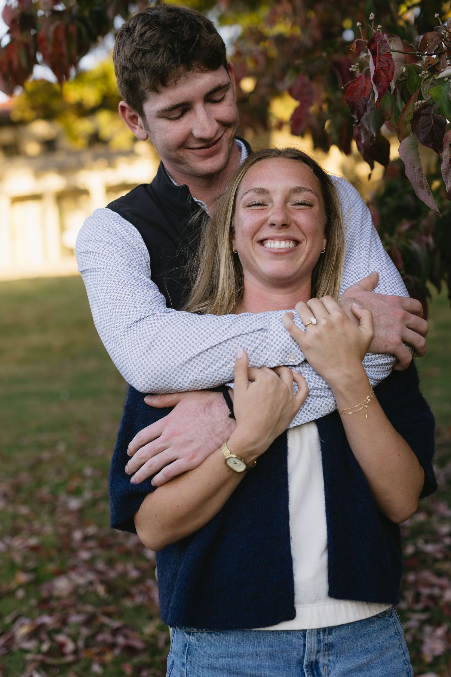 Couple sharing intimate embraces and laughter against autumn foliage background.