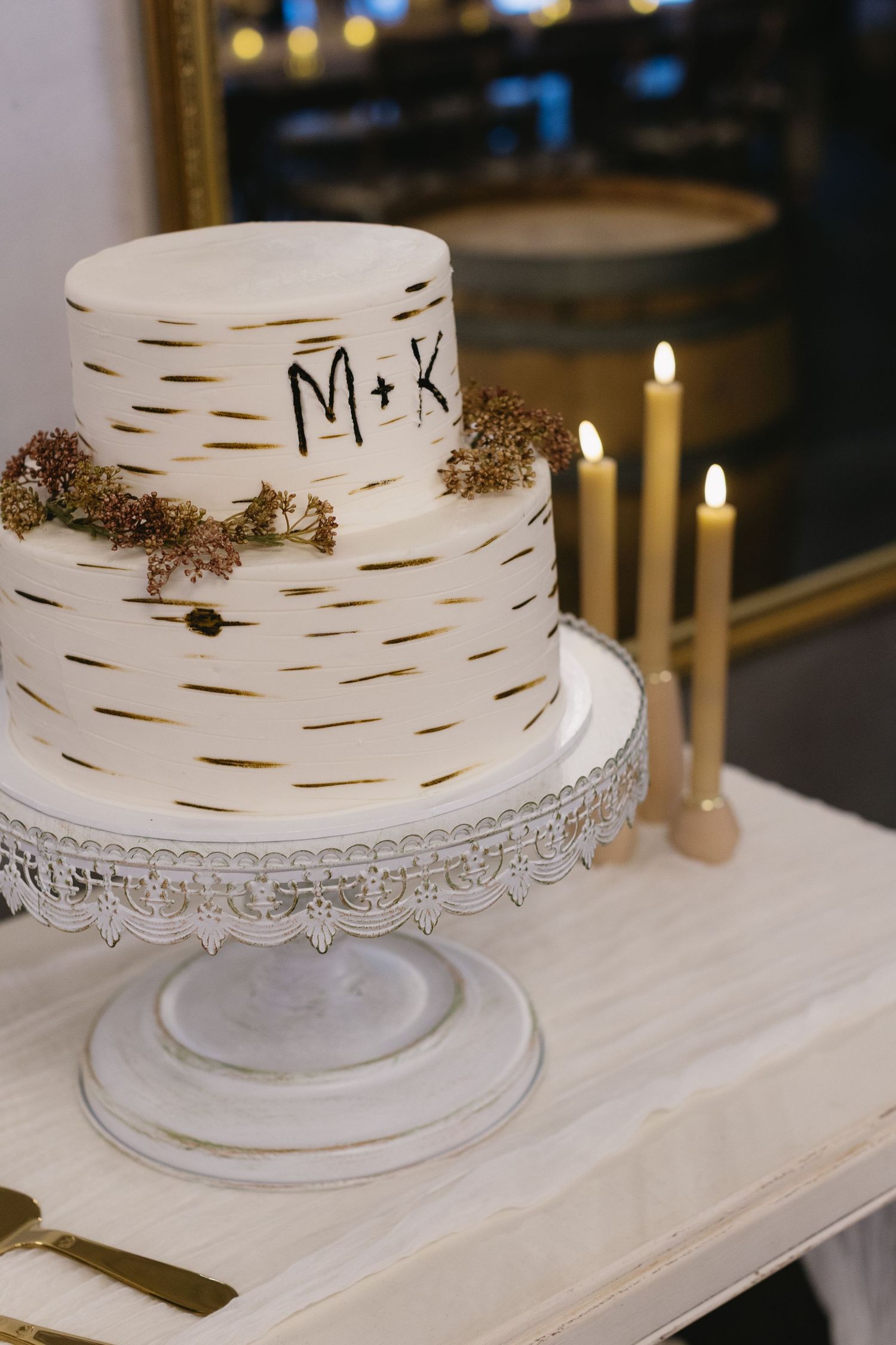 White wedding cake with birch bark texture design and decorative lace trim on display.