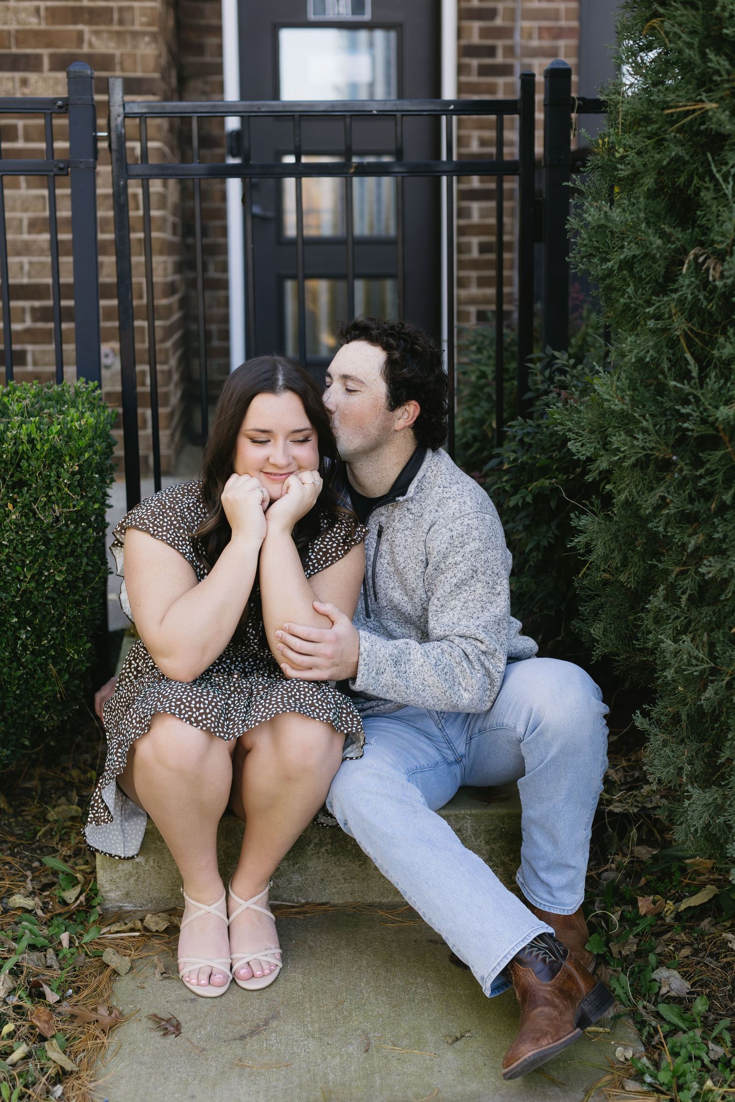 Couple in casual attire sharing intimate moments while sitting on concrete steps.