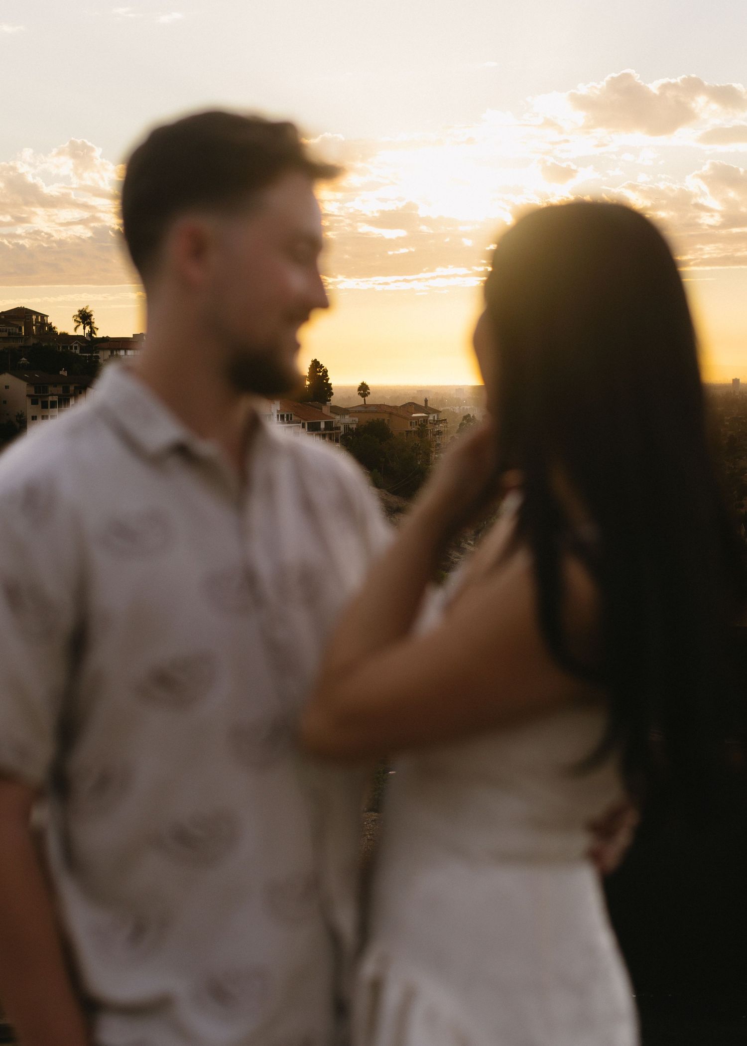 A couple sharing tender moments against a golden sunset backdrop.
