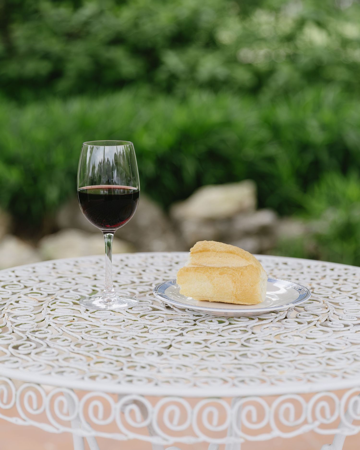 White decorative table with wine glasses and bread on an outdoor patio.