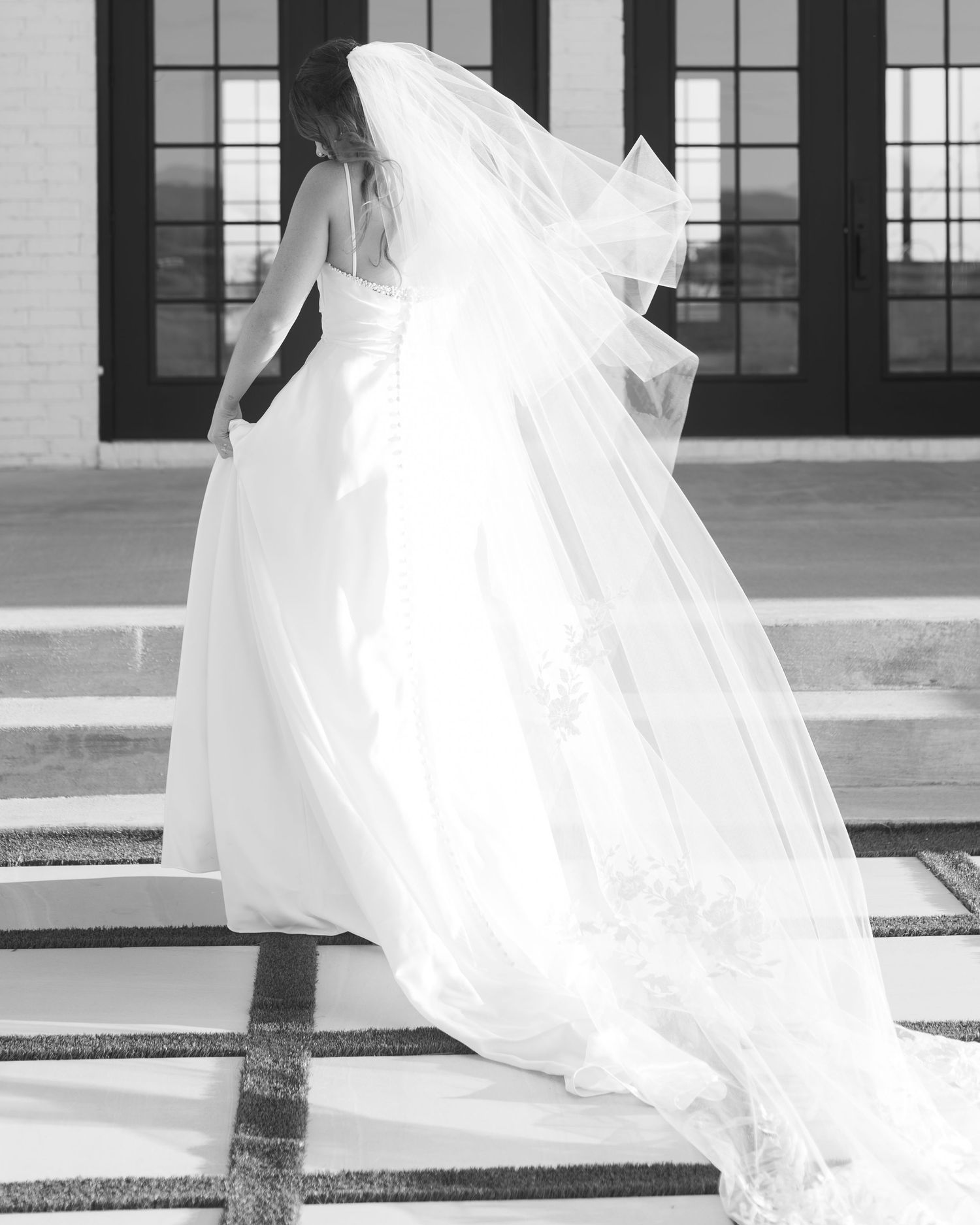 A series of artistic shots capturing a flowing white wedding dress and veil against a modern building facade.
