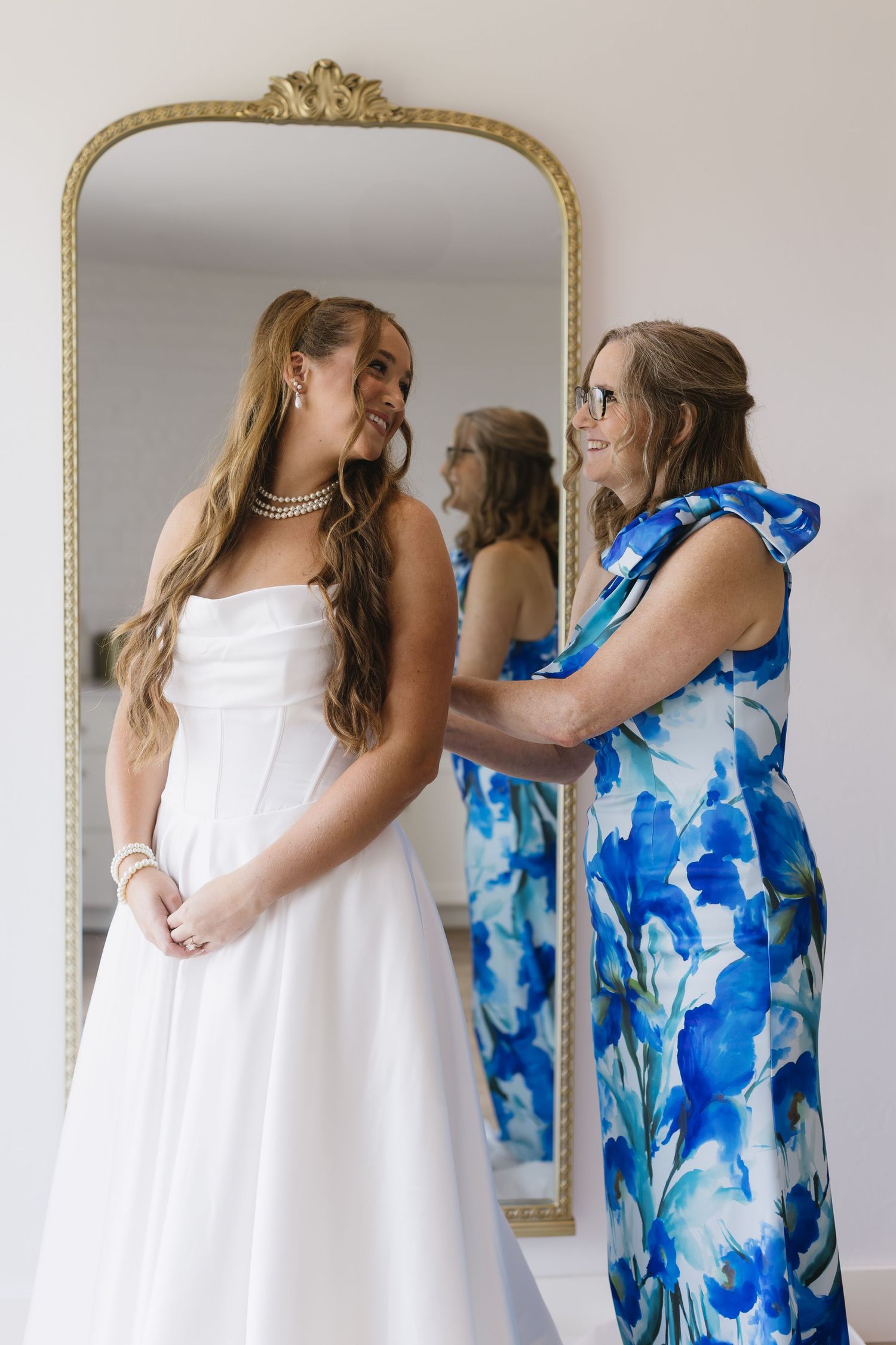 Wedding scene reflected in ornate gold mirror showing bridal preparations.