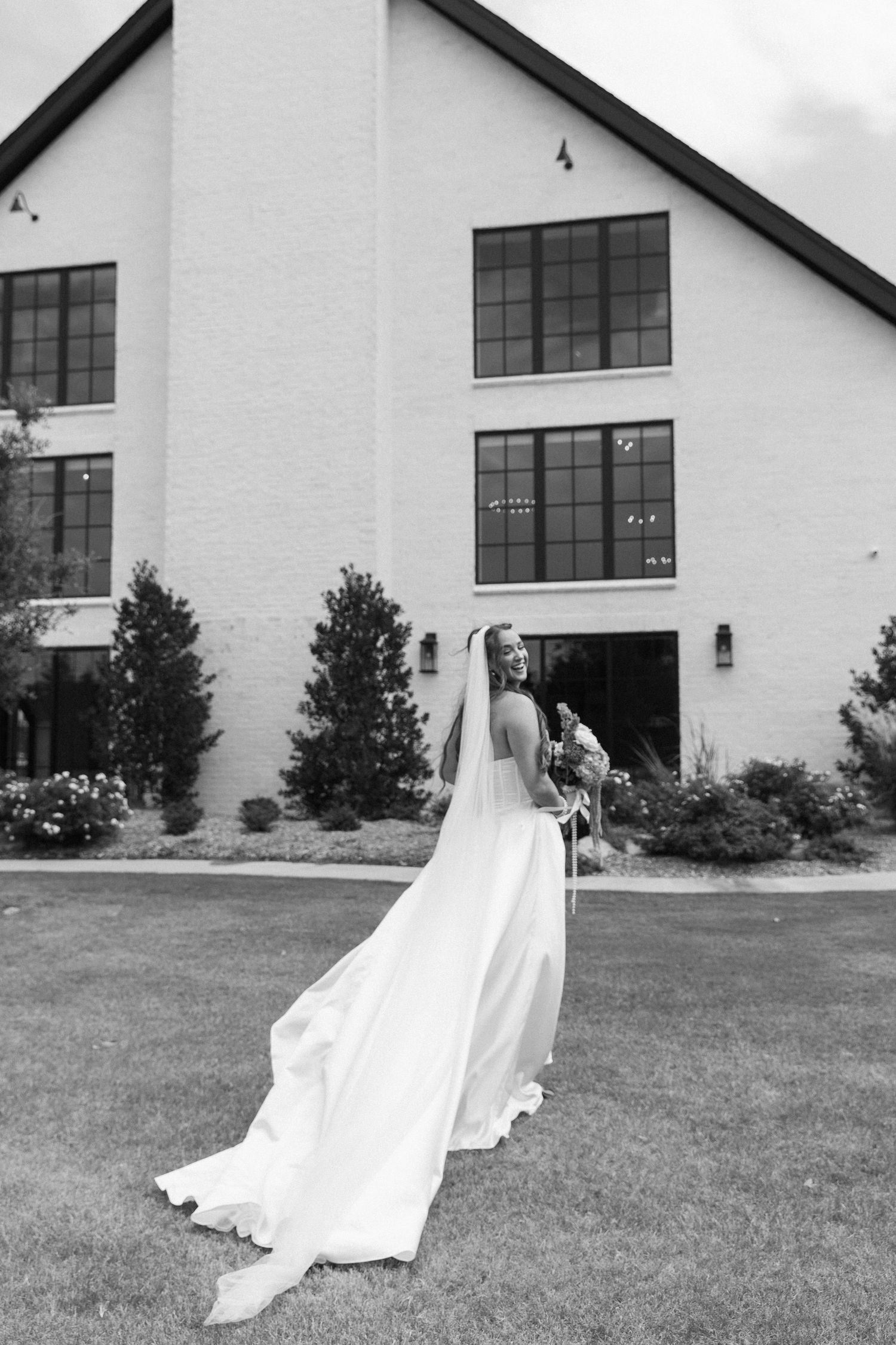 Wedding dress silhouette against white church building with large windows.
