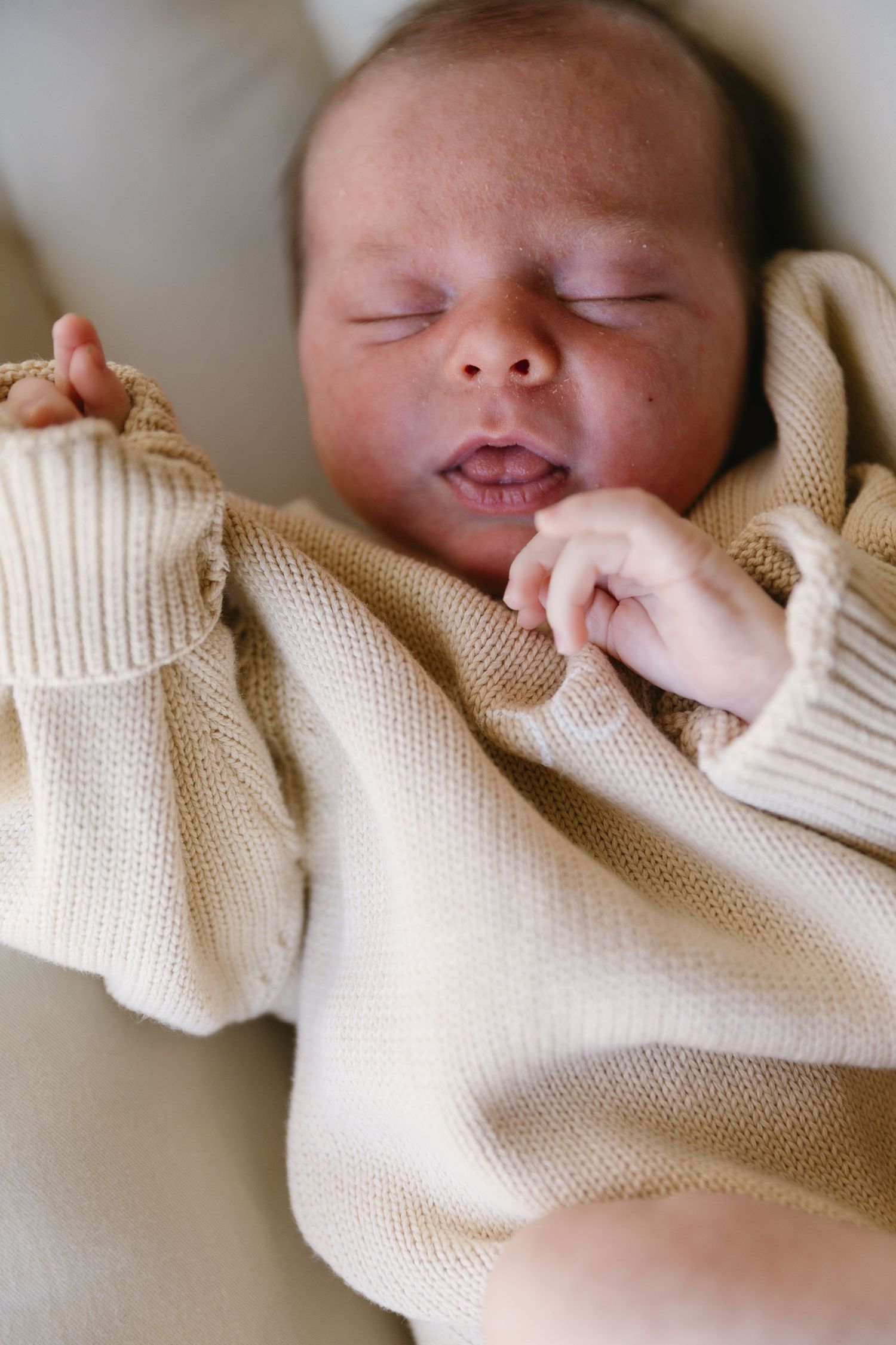 Sleeping newborn wrapped in cozy cream knit blanket shown in sequential close-up shots.
