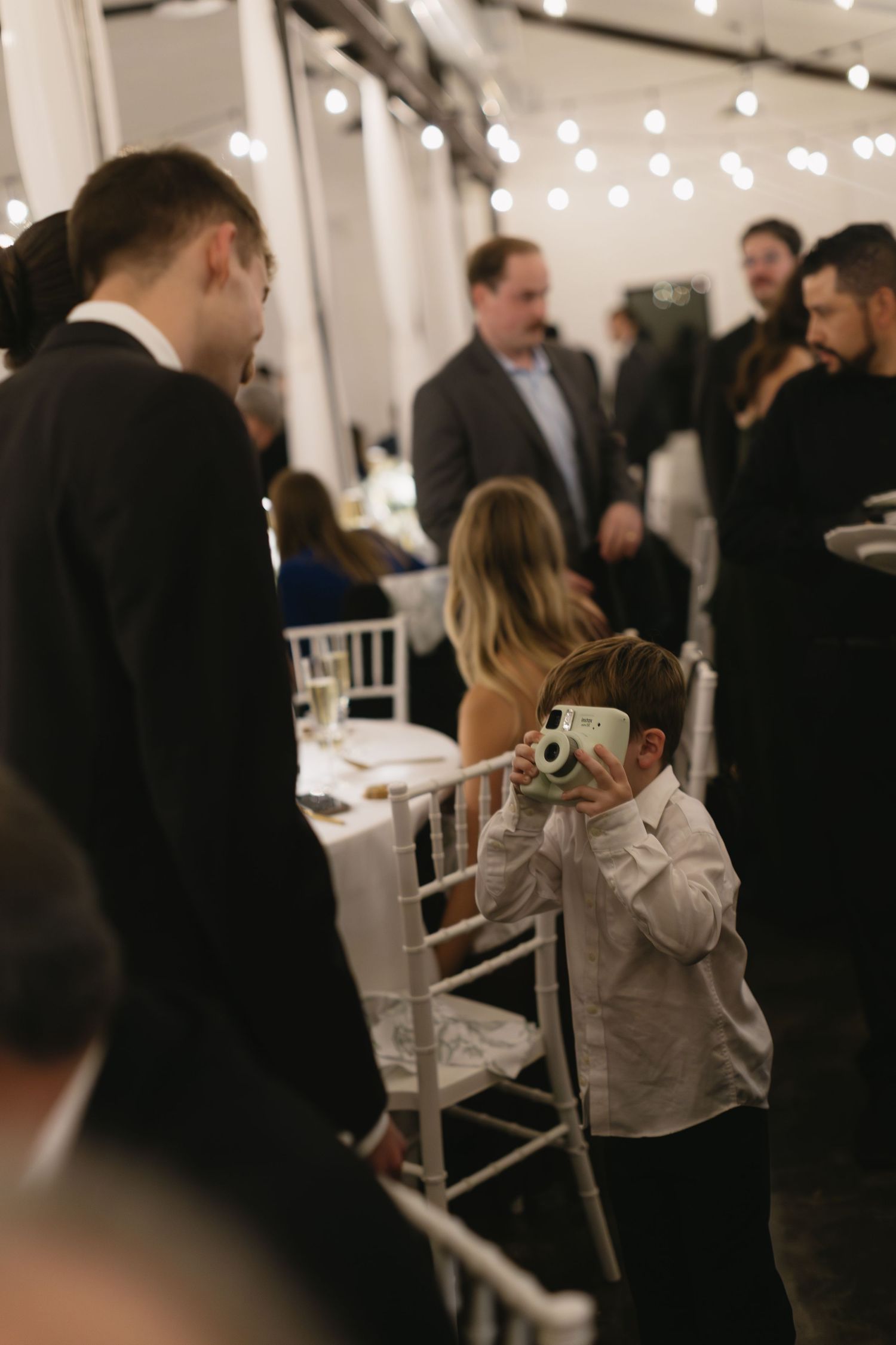 Young guest taking photos at a wedding reception with a vintage camera.