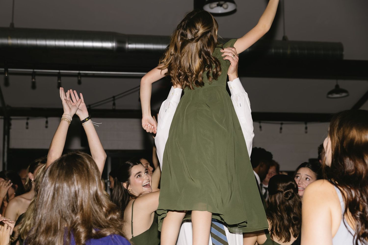 Wedding guests dancing and celebrating on a dark dance floor at a reception.