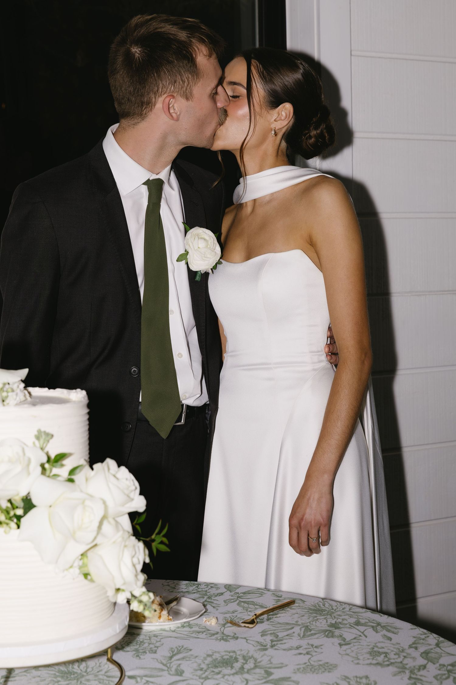 A wedding couple shares intimate moments near their white wedding cake.