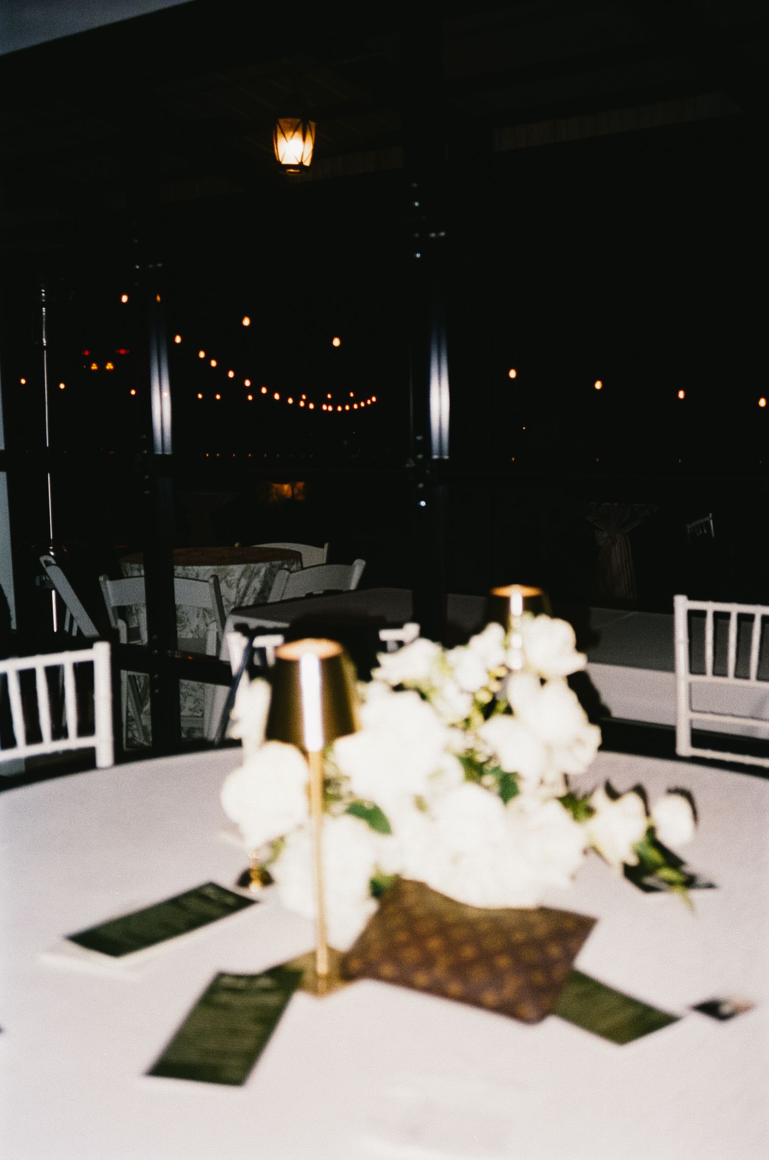 Evening wedding reception table setup with white linens and glowing candle centerpieces.