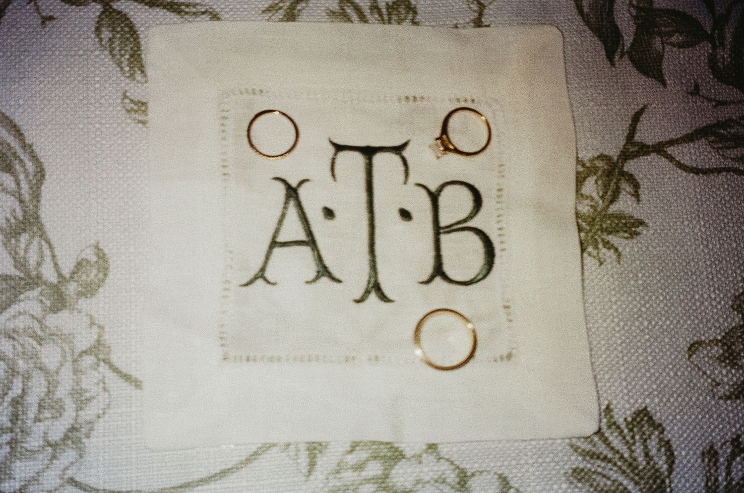A monogrammed wedding detail showing ATB initials with wedding rings.