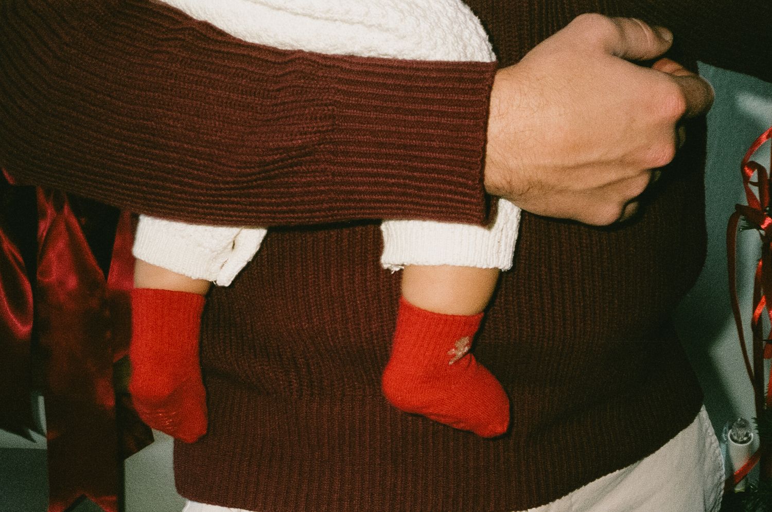 A pair of bright red Christmas stockings hanging side by side against a dark background.