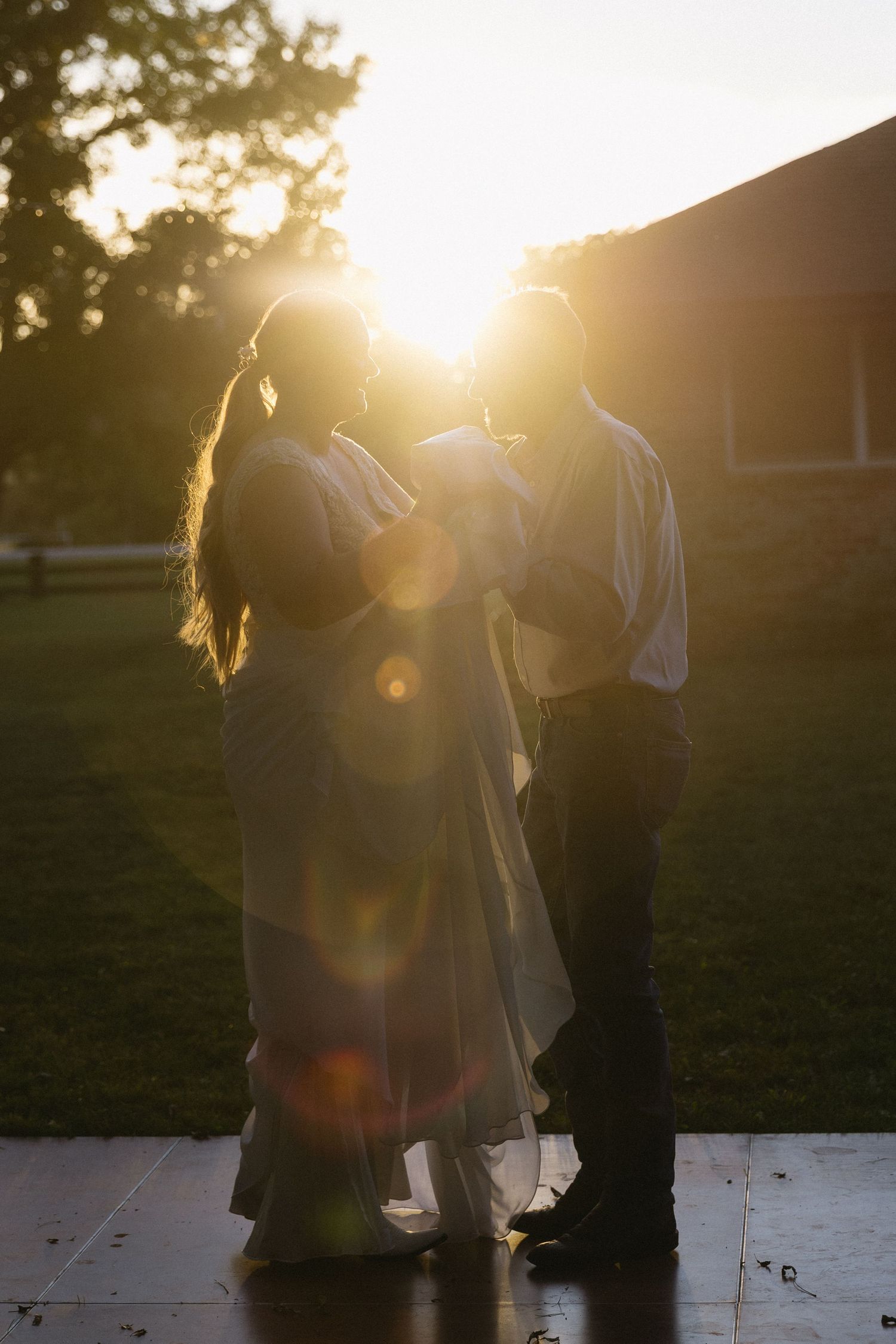 A couple dances together during golden hour with sunlight creating a romantic silhouette.