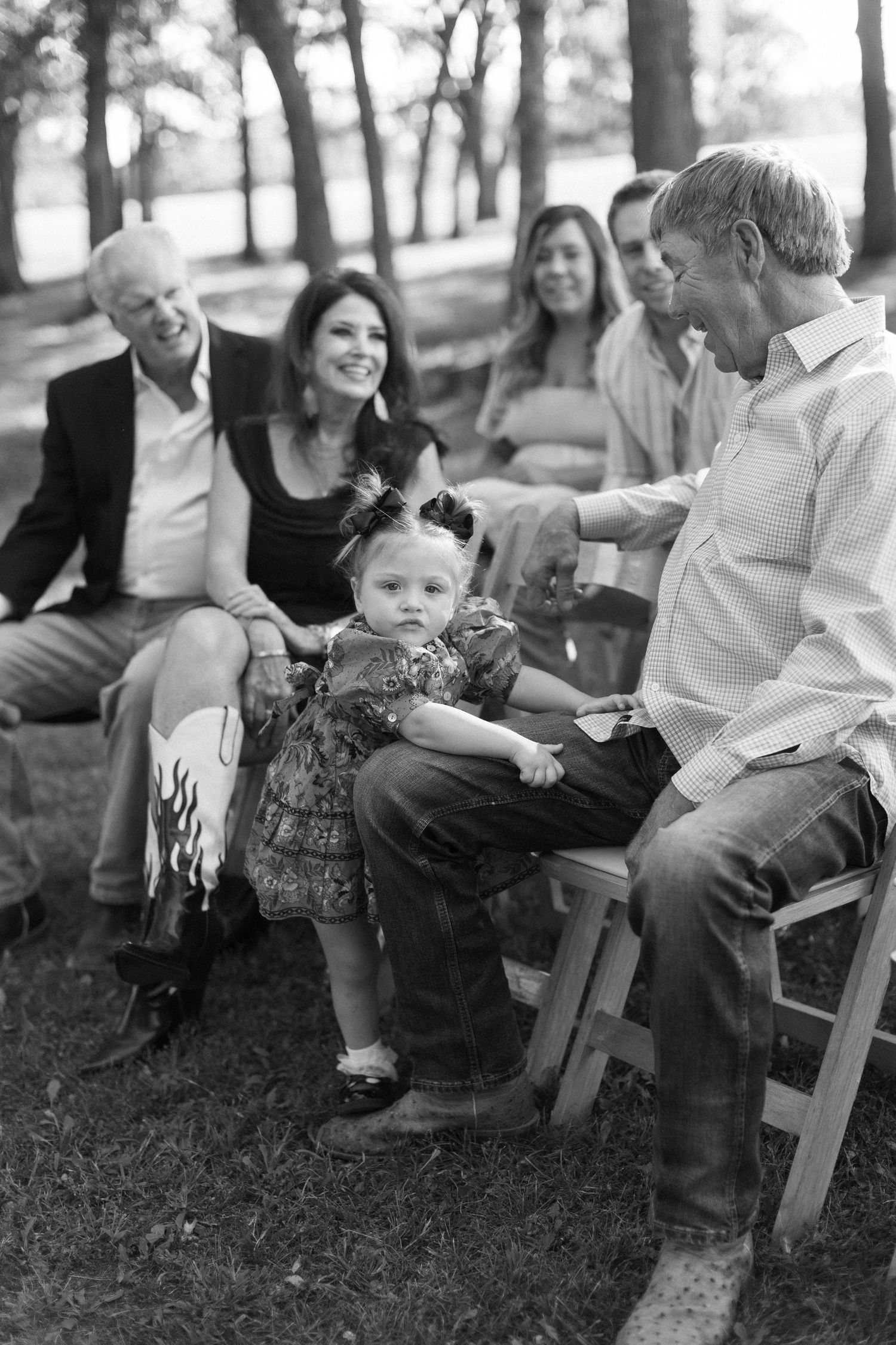 Black and white photo of wedding guests seated on chairs outdoors.