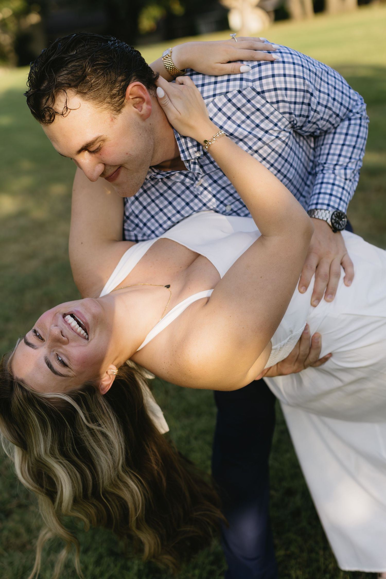 Romantic couple shares tender embrace in golden sunlight during outdoor photoshoot.