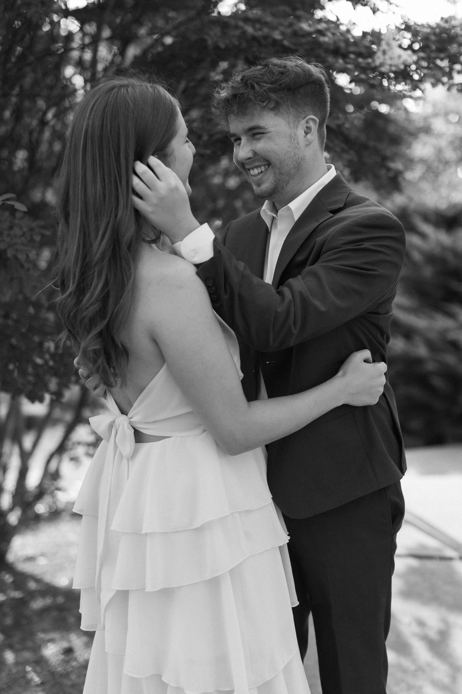 A romantic moment captured in black and white as a couple embraces in an outdoor setting.