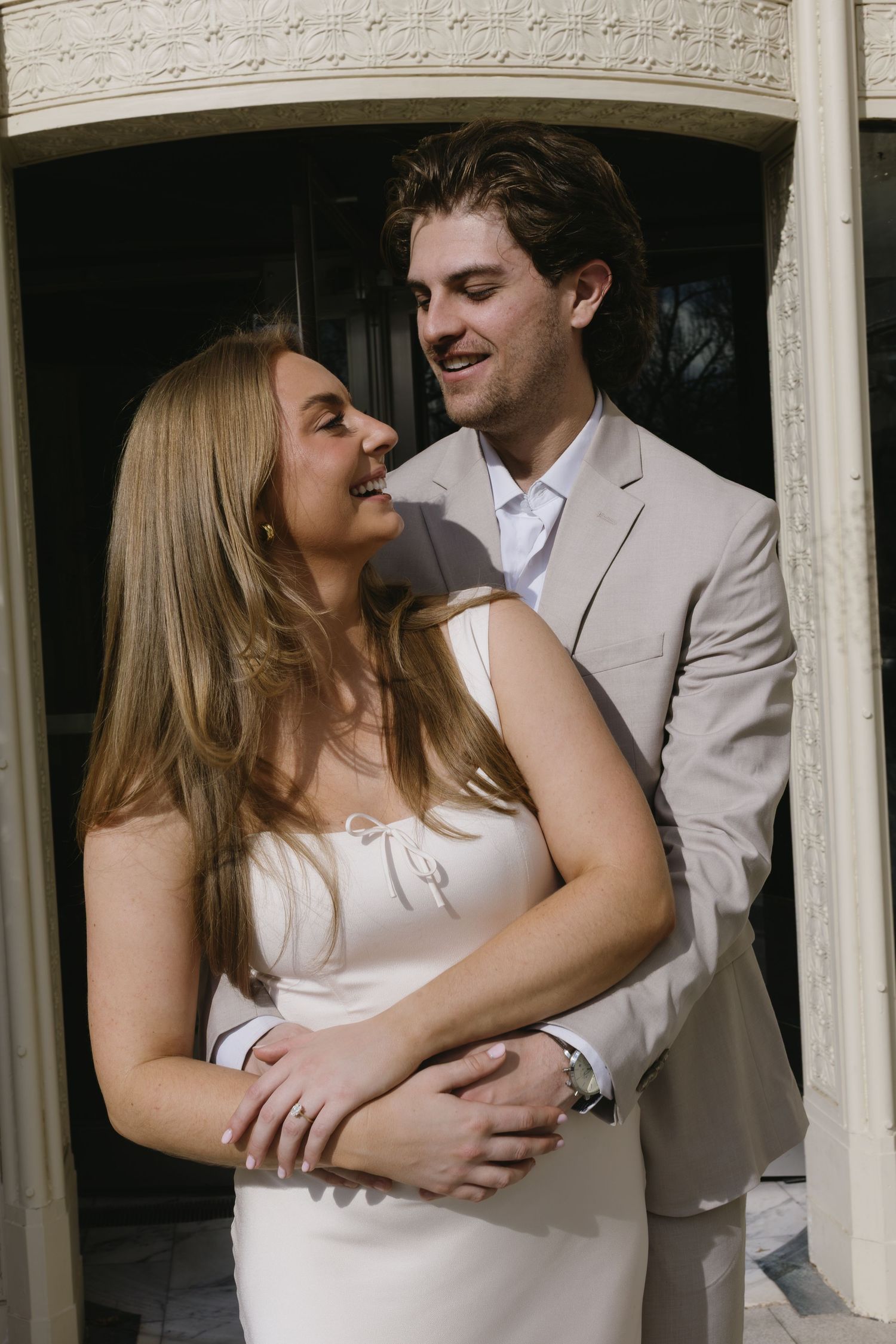 A couple shares a joyful moment while embracing in an ornate doorway.