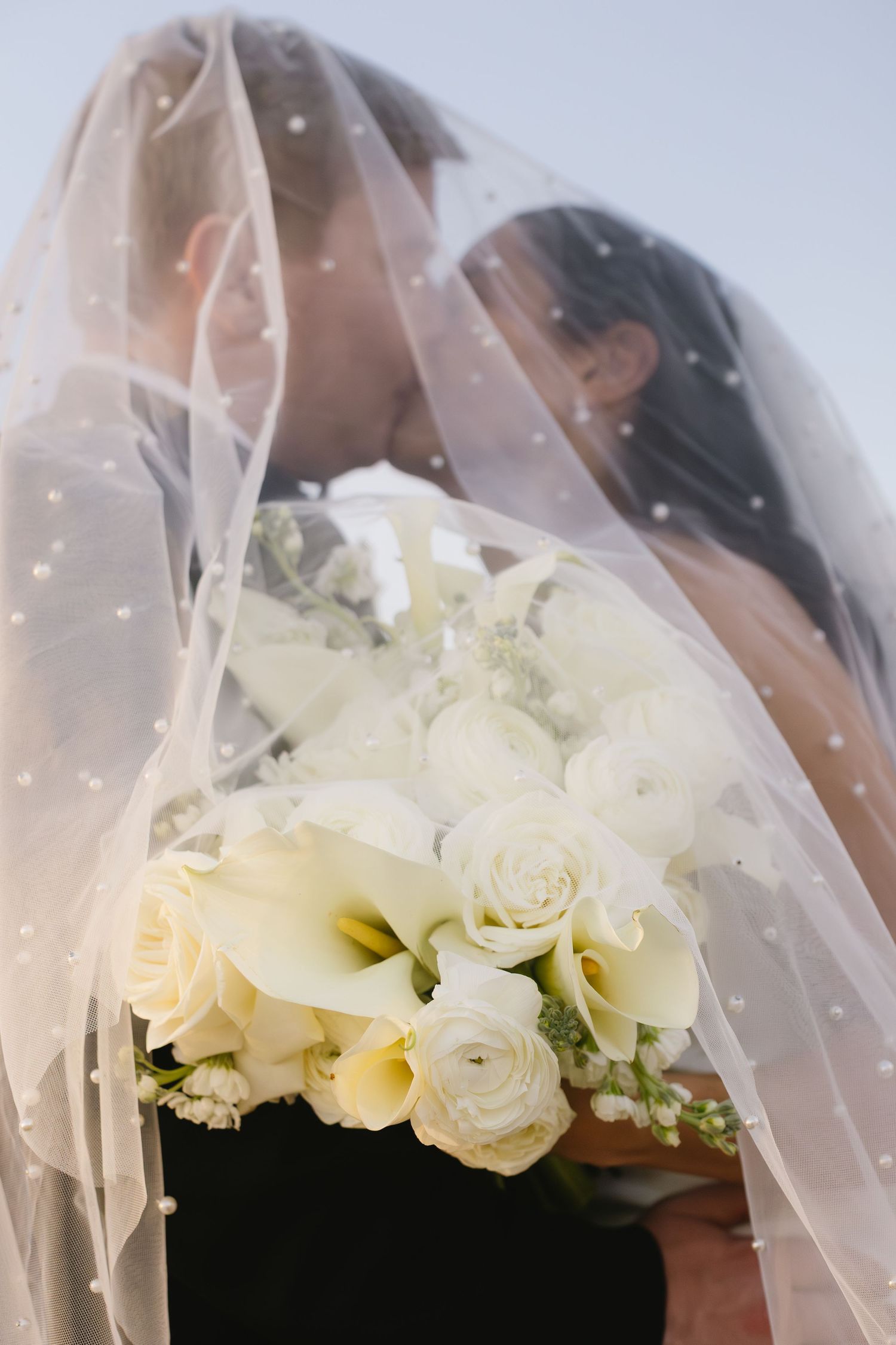 Elegant white roses and veil arrangement captured in soft, dreamy lighting.