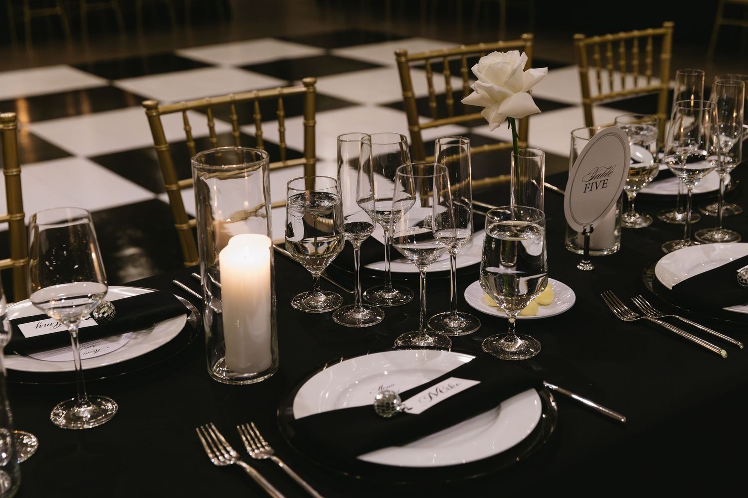 Black and white table settings with elegant glassware and place settings at a formal event.