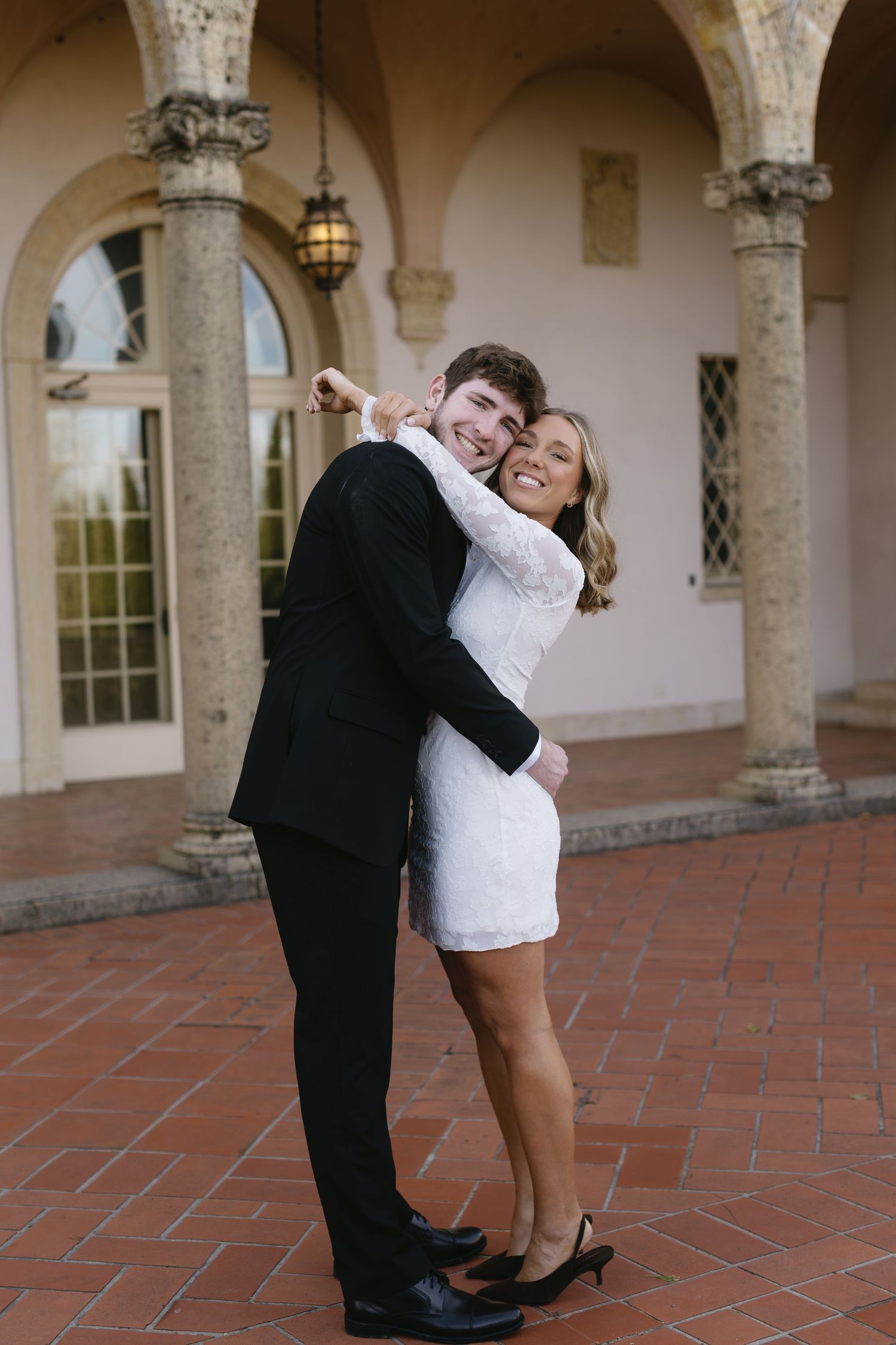 Dancing sequence captured in an elegant colonnade with terracotta flooring and stone archways.