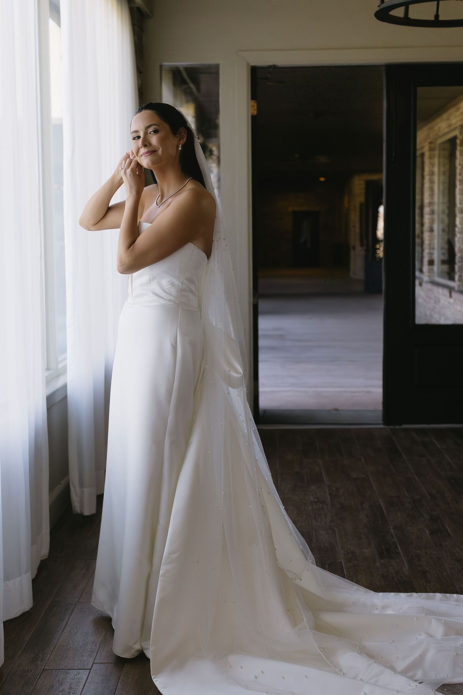 Elegant white wedding gown with flowing train photographed in an indoor venue with natural light.