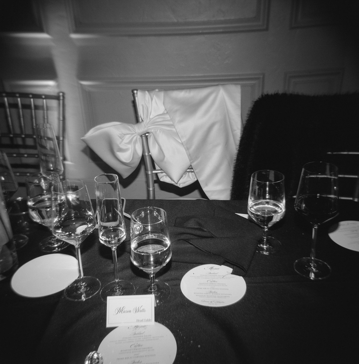 Elegant black and white table setting with wine glasses and place cards at a formal event.