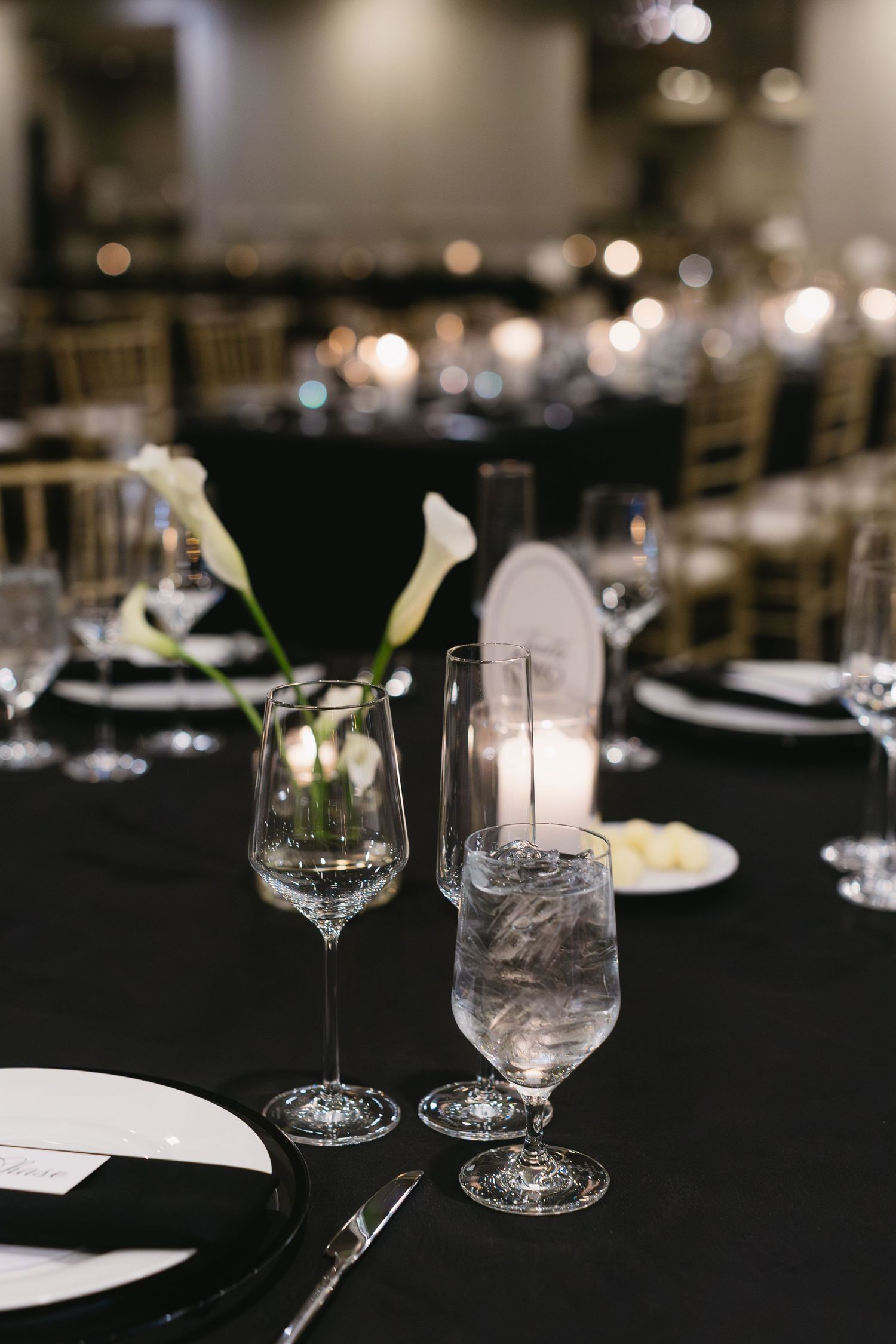 Black and white table settings with crystal glassware create dramatic wedding reception ambiance.