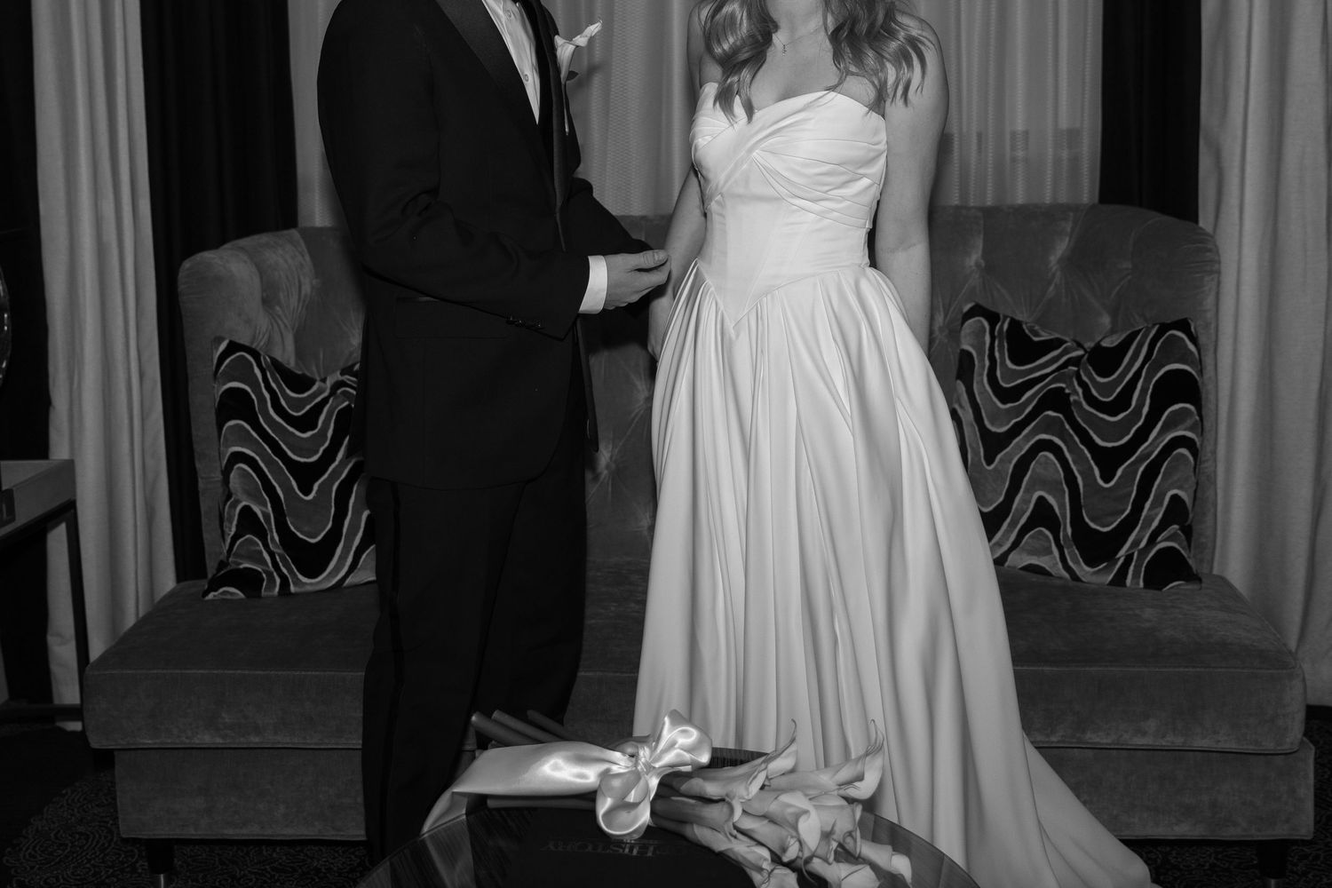 Wedding couple in formal attire sharing intimate moment in elegant indoor setting.