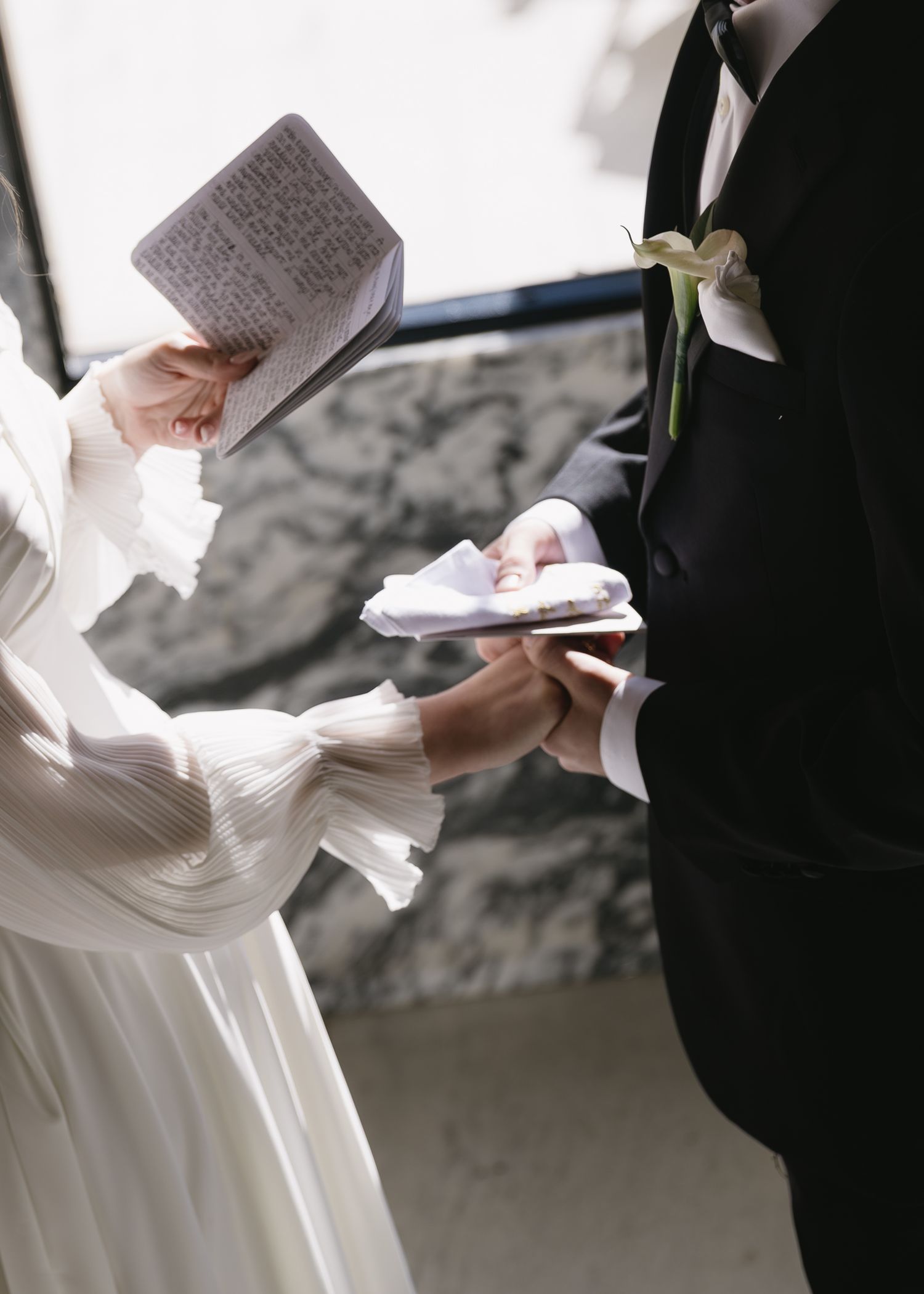 Close-up of wedding couple exchanging vows or reading letters in an intimate setting.