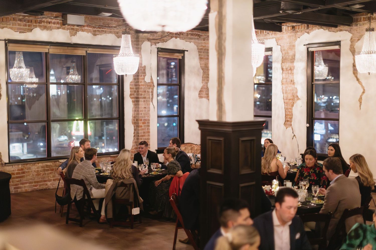 Wide view of a restaurant dining room with exposed brick walls and pendant lighting.