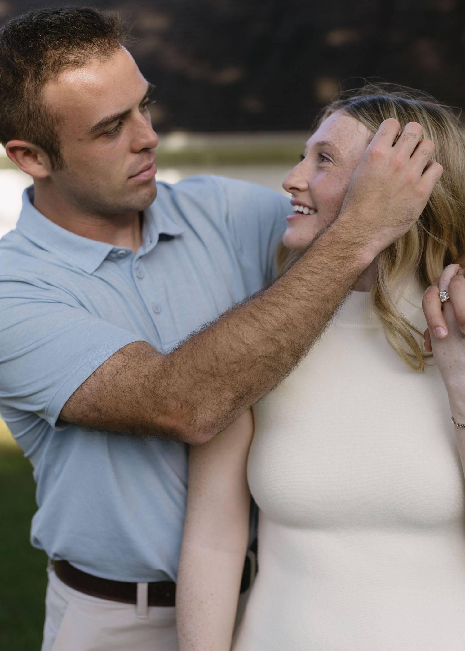 Romantic couple in light and dark clothing share an intimate moment outdoors during a photo session.