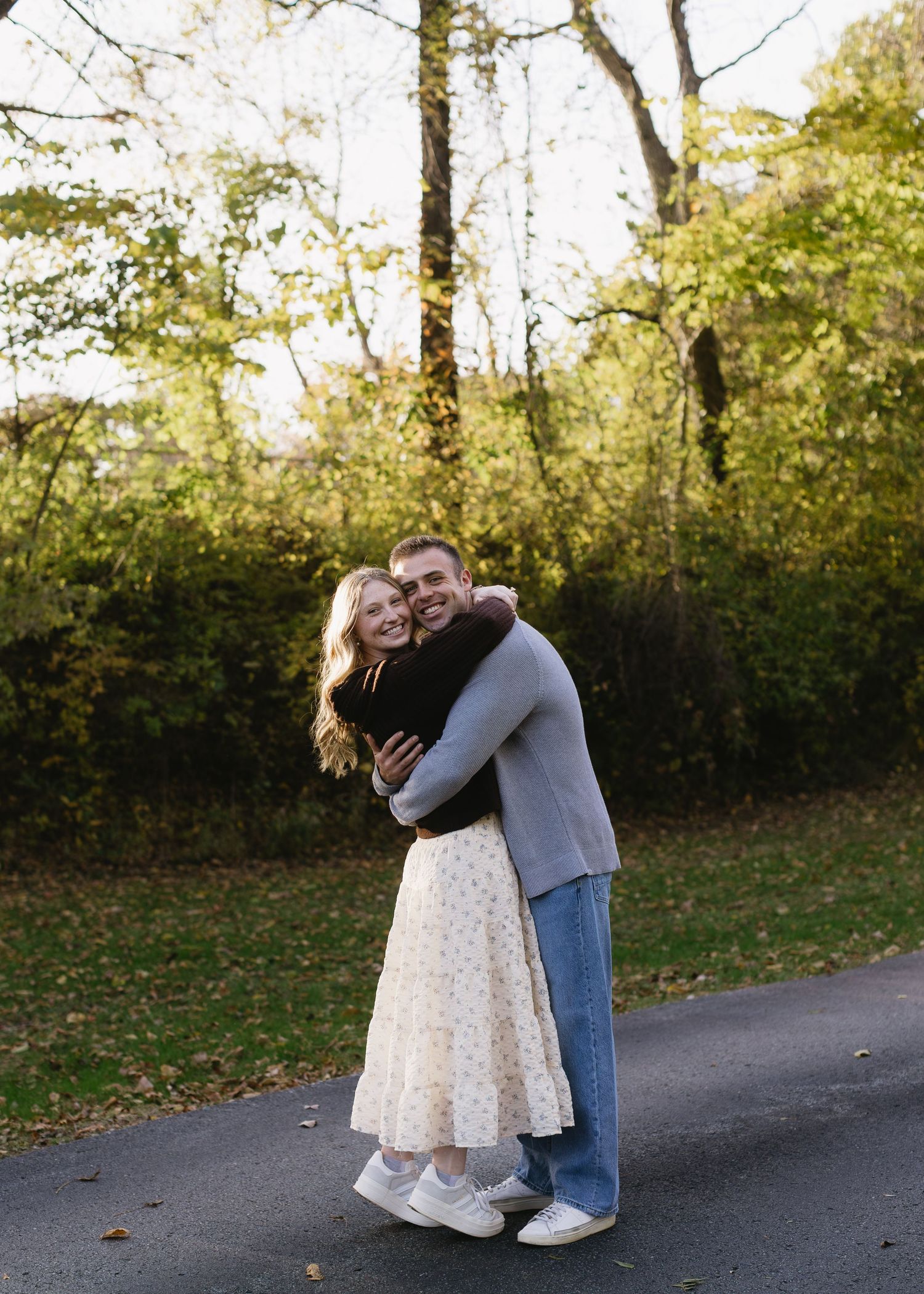 A romantic embrace captured on a wooded path in autumn.