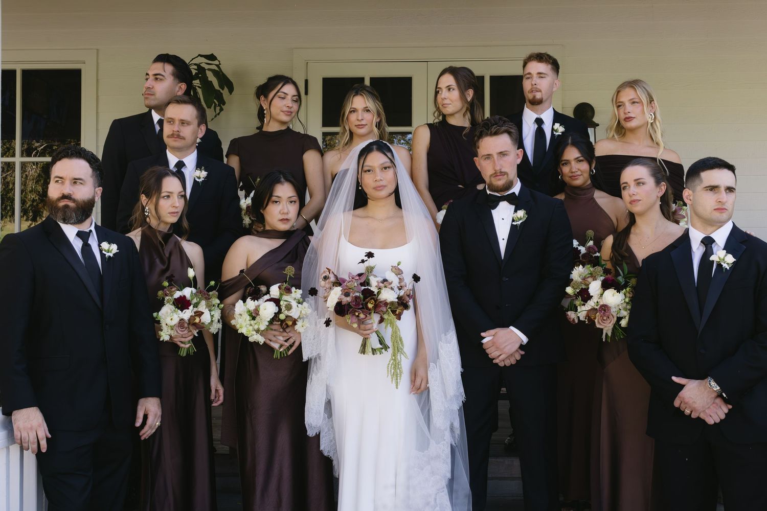Wedding party members in formal attire pose together in an elegant indoor setting.