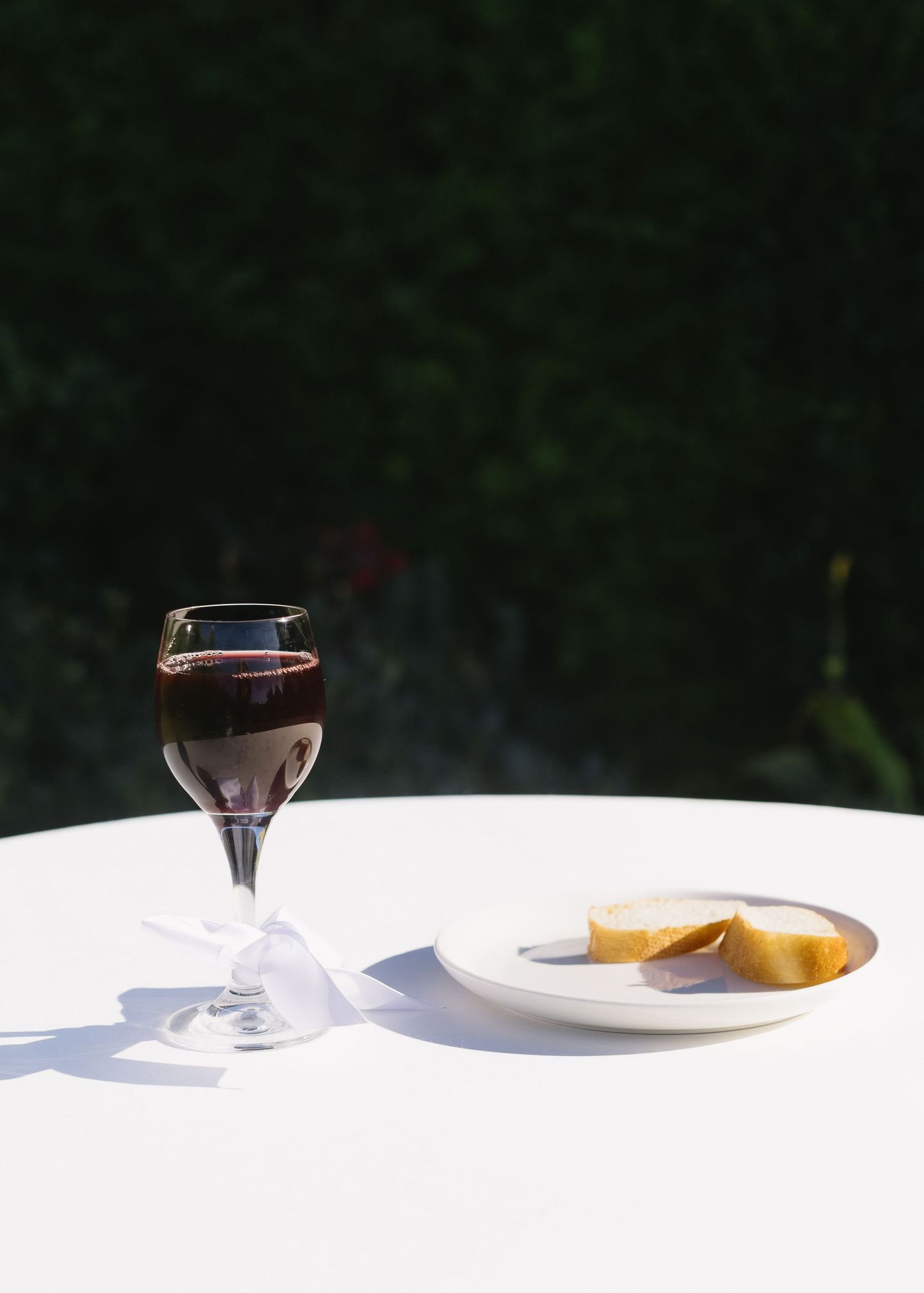 Minimalist table setting with wine glasses casting shadows on white tablecloth.
