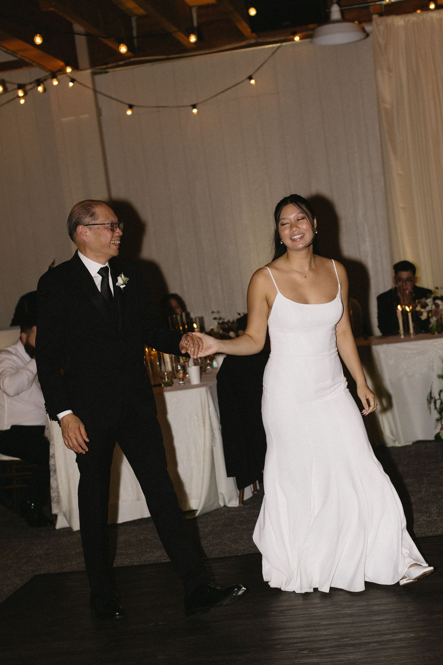 Couple dancing at their wedding reception with string lights overhead.