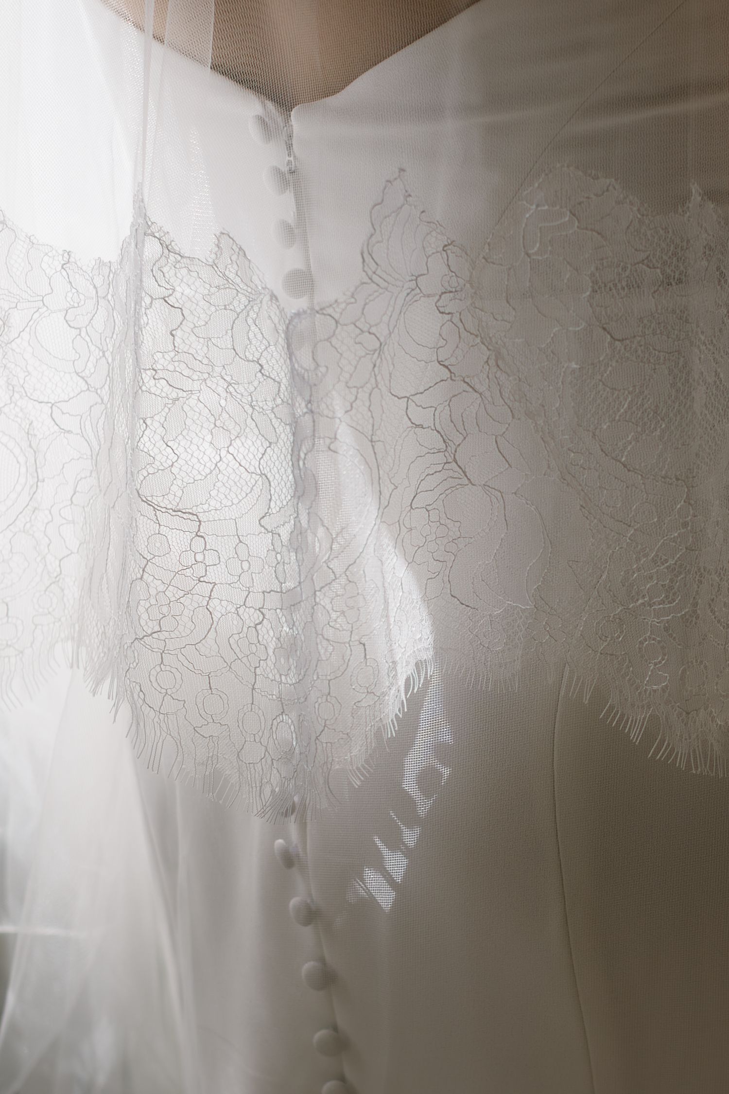 Delicate white lace curtains with intricate floral patterns filter soft natural light through a window.
