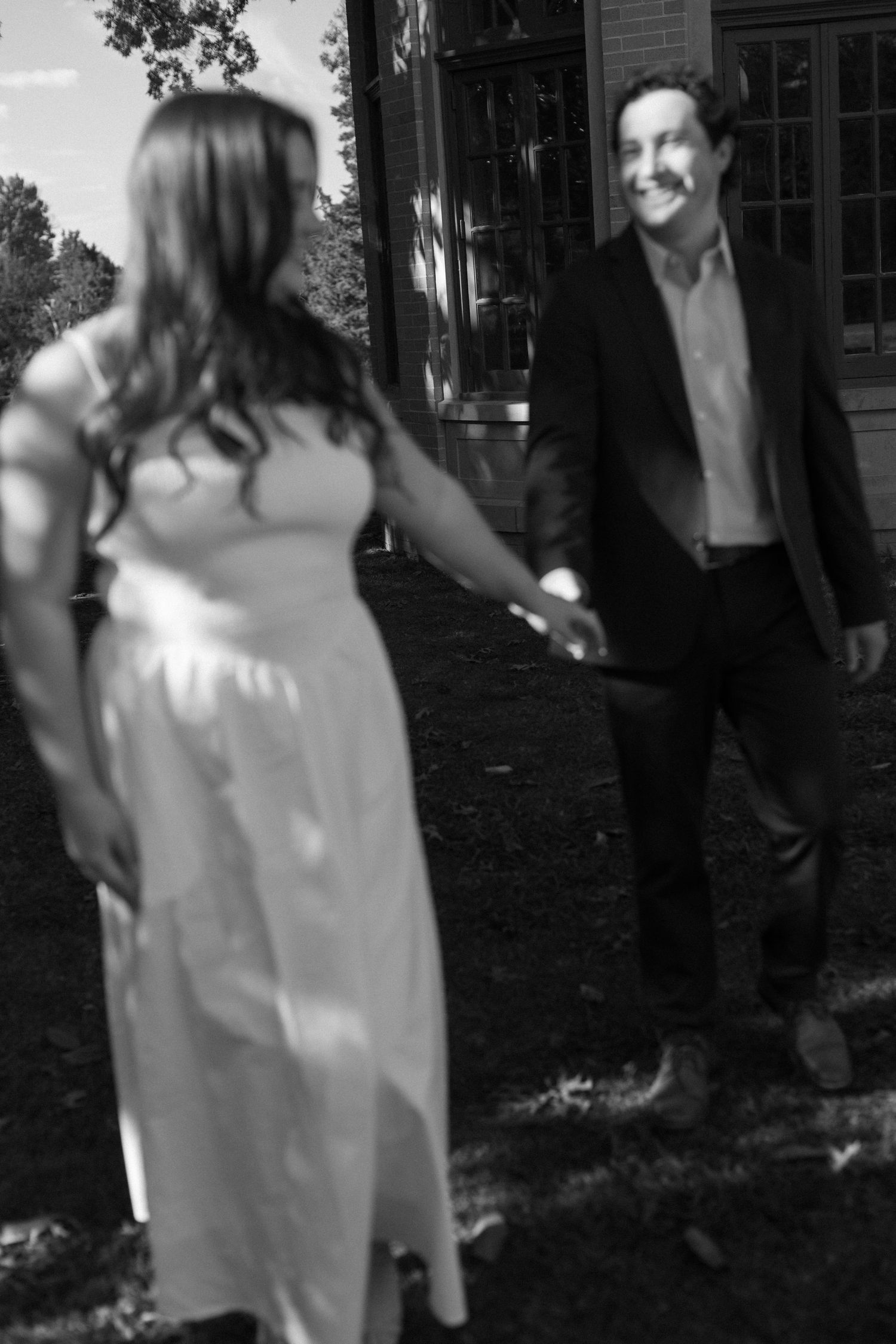 A black and white photo of a couple sharing a playful moment outdoors.