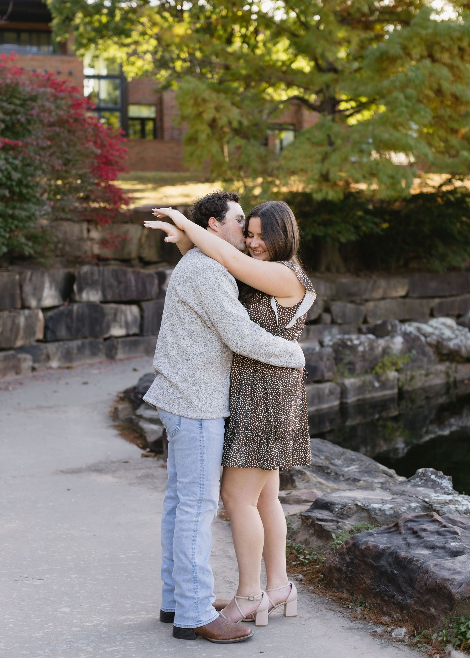 A couple sharing an intimate embrace on a stone path surrounded by autumn foliage.