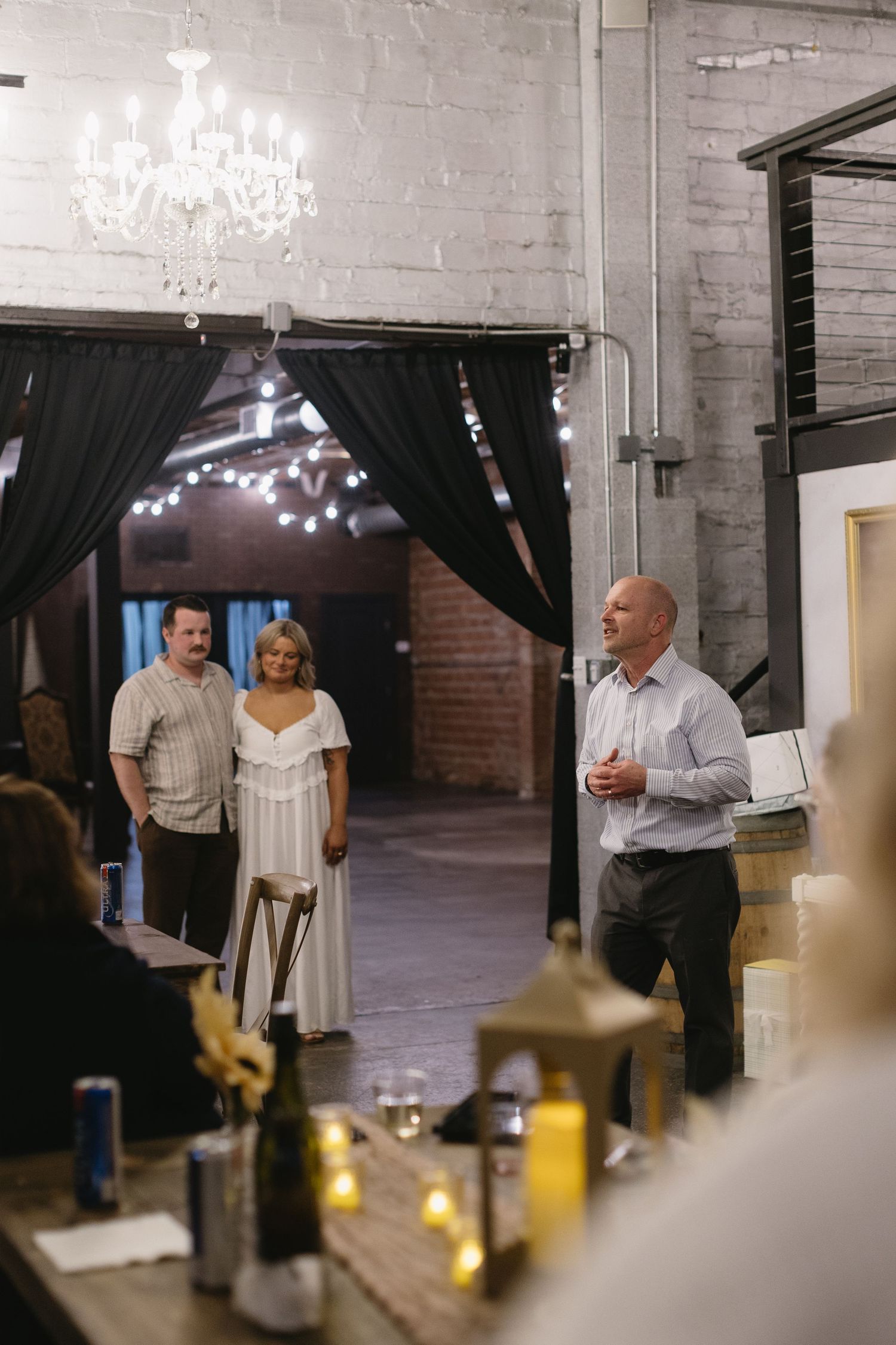 Guests mingle and converse during an indoor reception with elegant chandeliers and candlelit ambiance.
