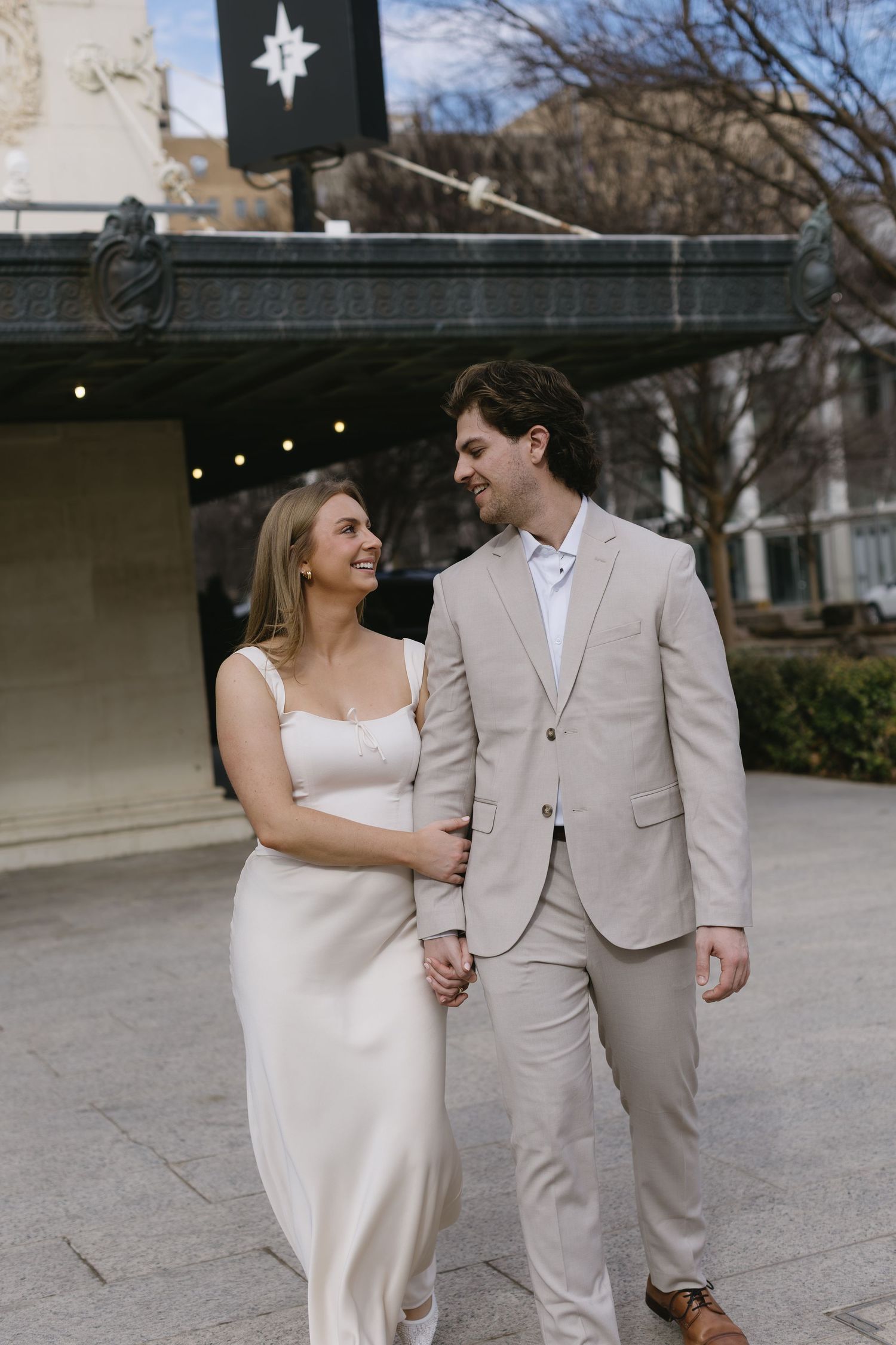 A couple in coordinated formal attire shares a joyful moment while walking together outdoors.