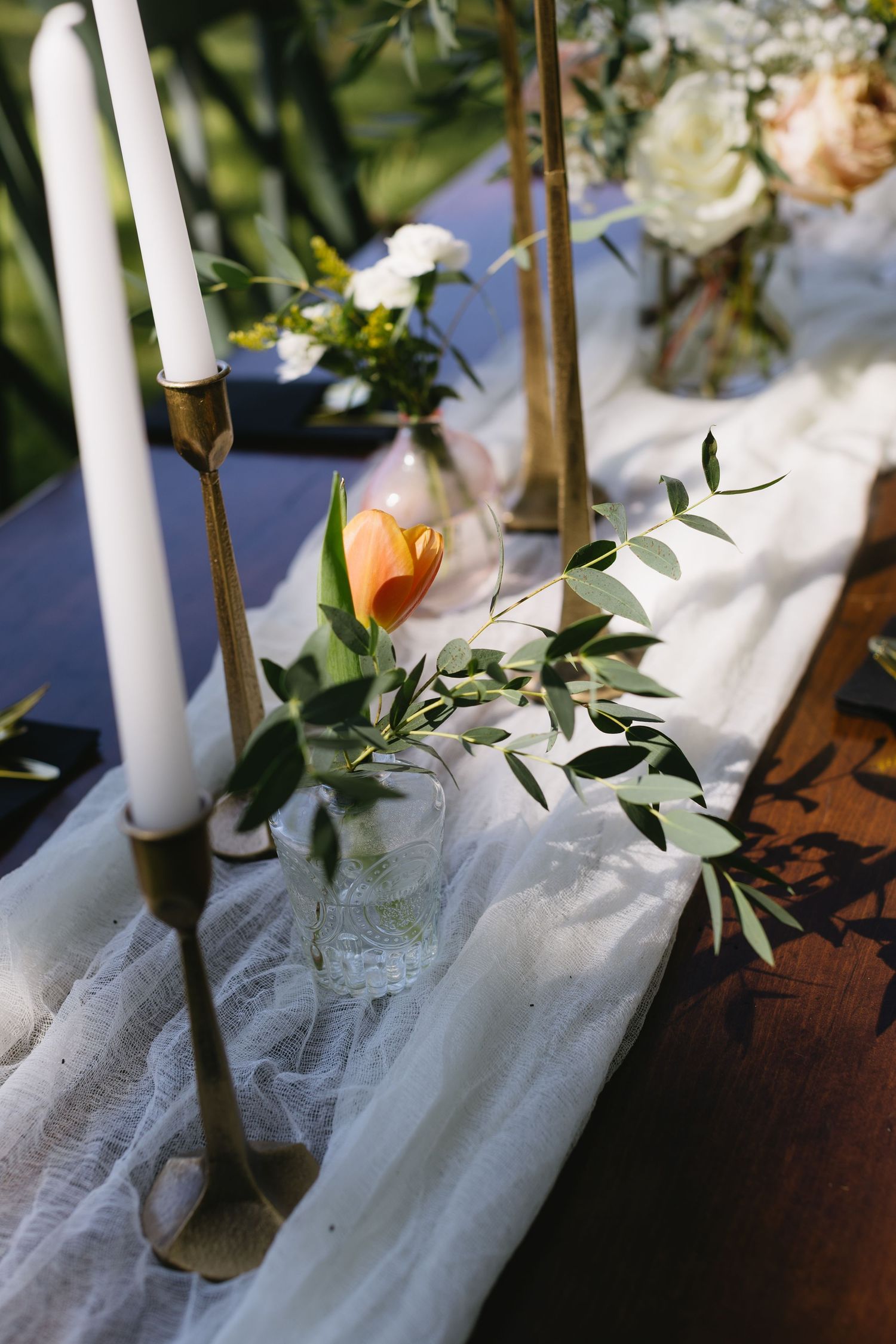 White candles and floral arrangements decorating a wedding table runner.