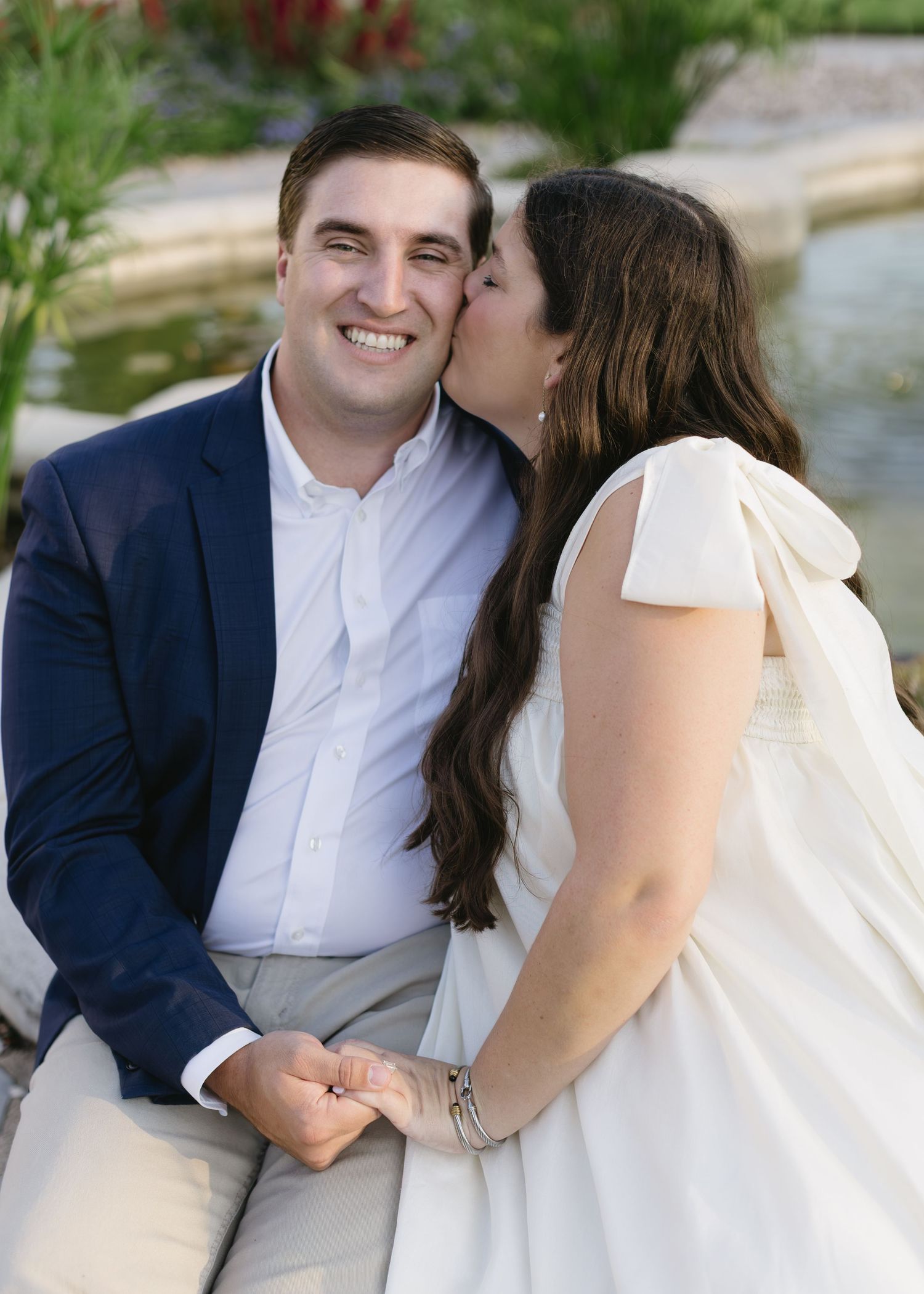 A couple shares intimate moments during their engagement photoshoot by a garden pond.