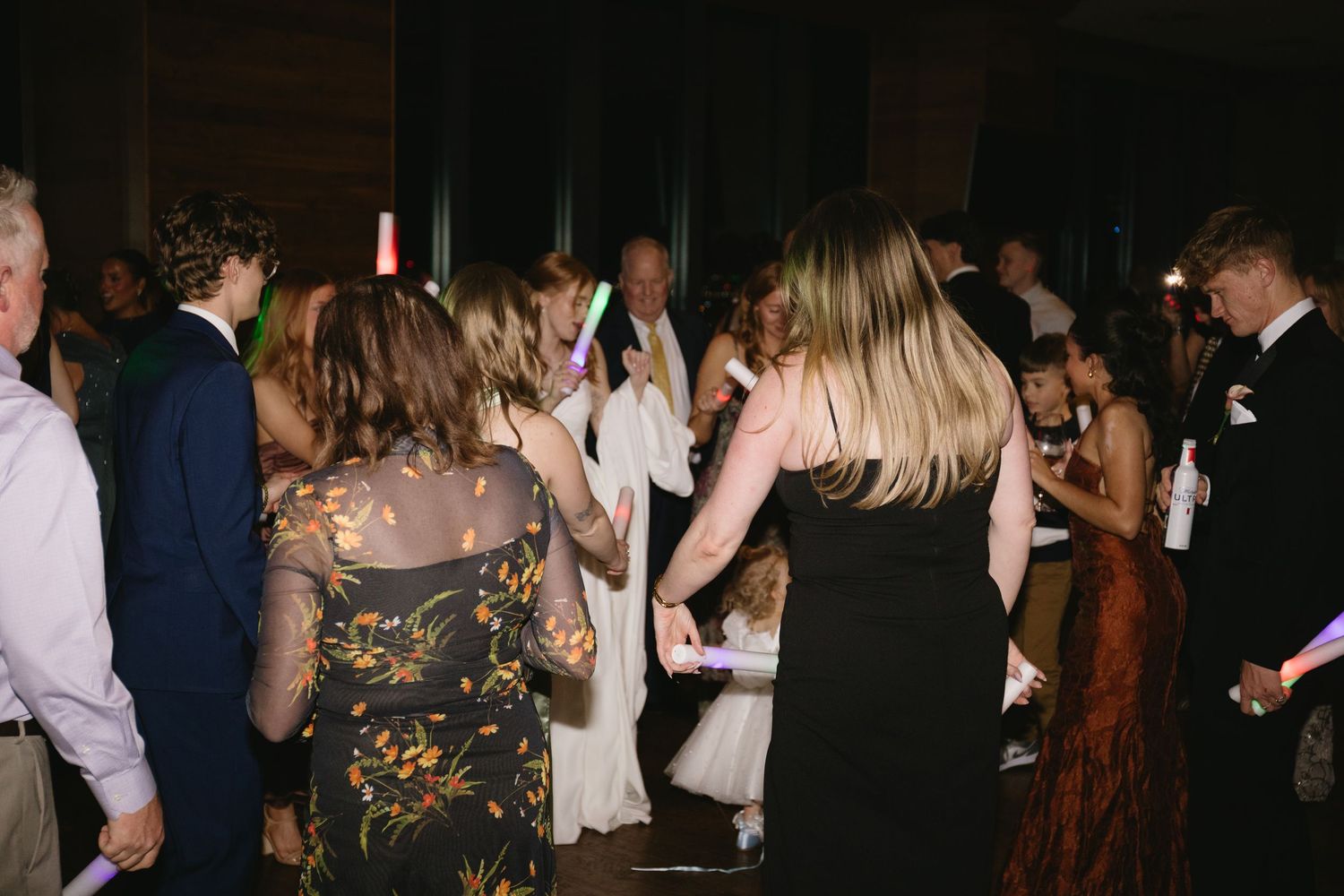 Dark reception venue with dancing guests creating silhouettes against dim lighting.