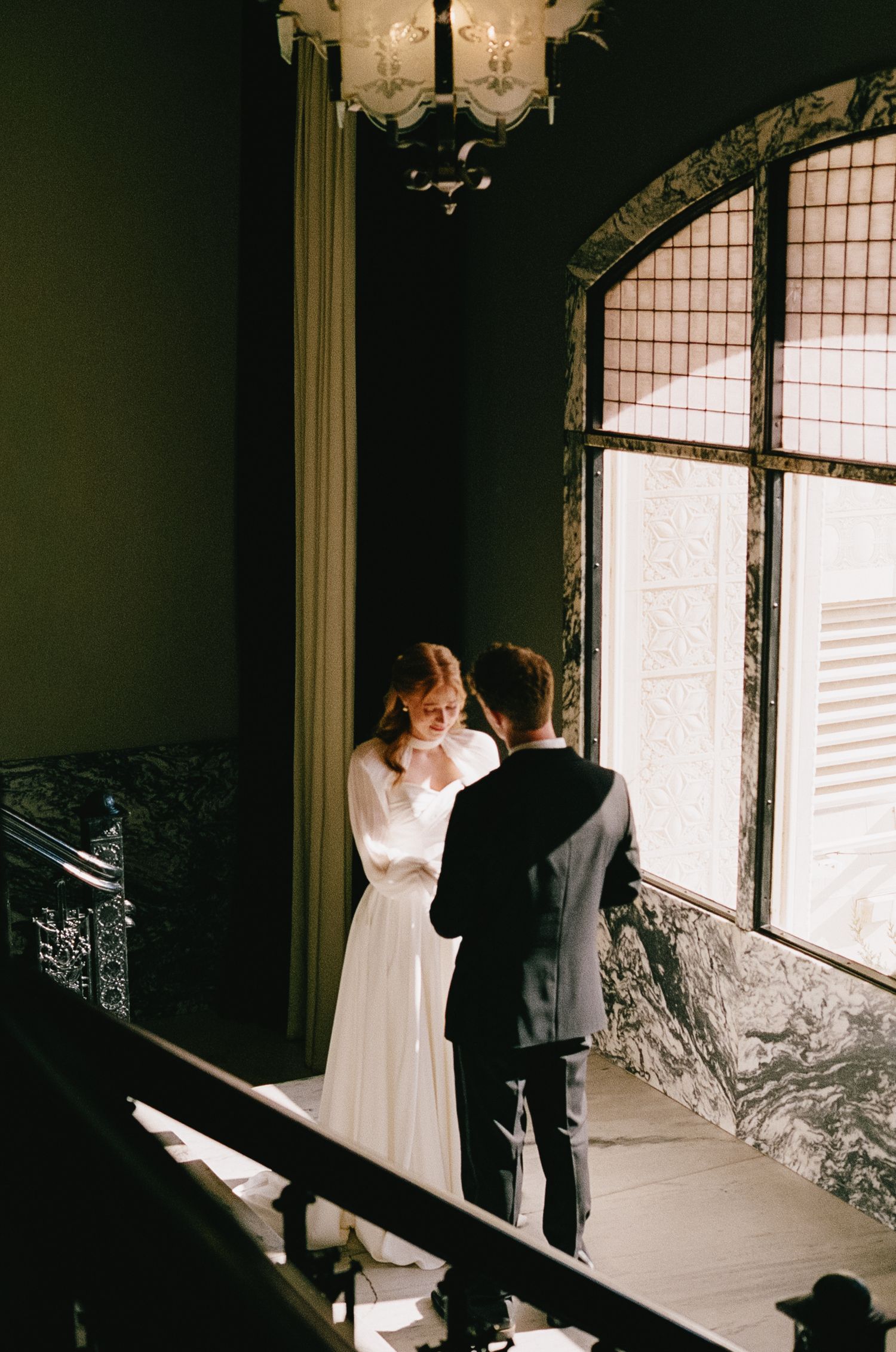 Elegant room with large windows and two people posing near natural light.