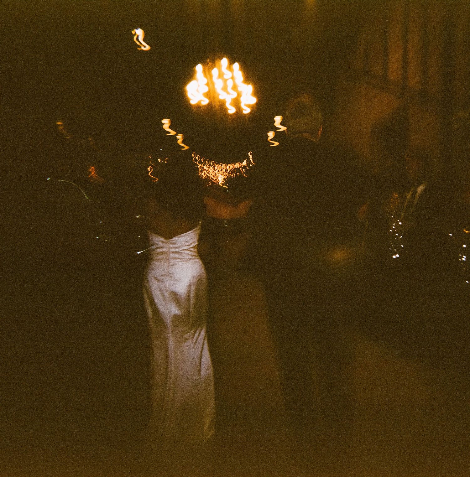 Wedding reception scene with glowing chandeliers and elegant white decor.
