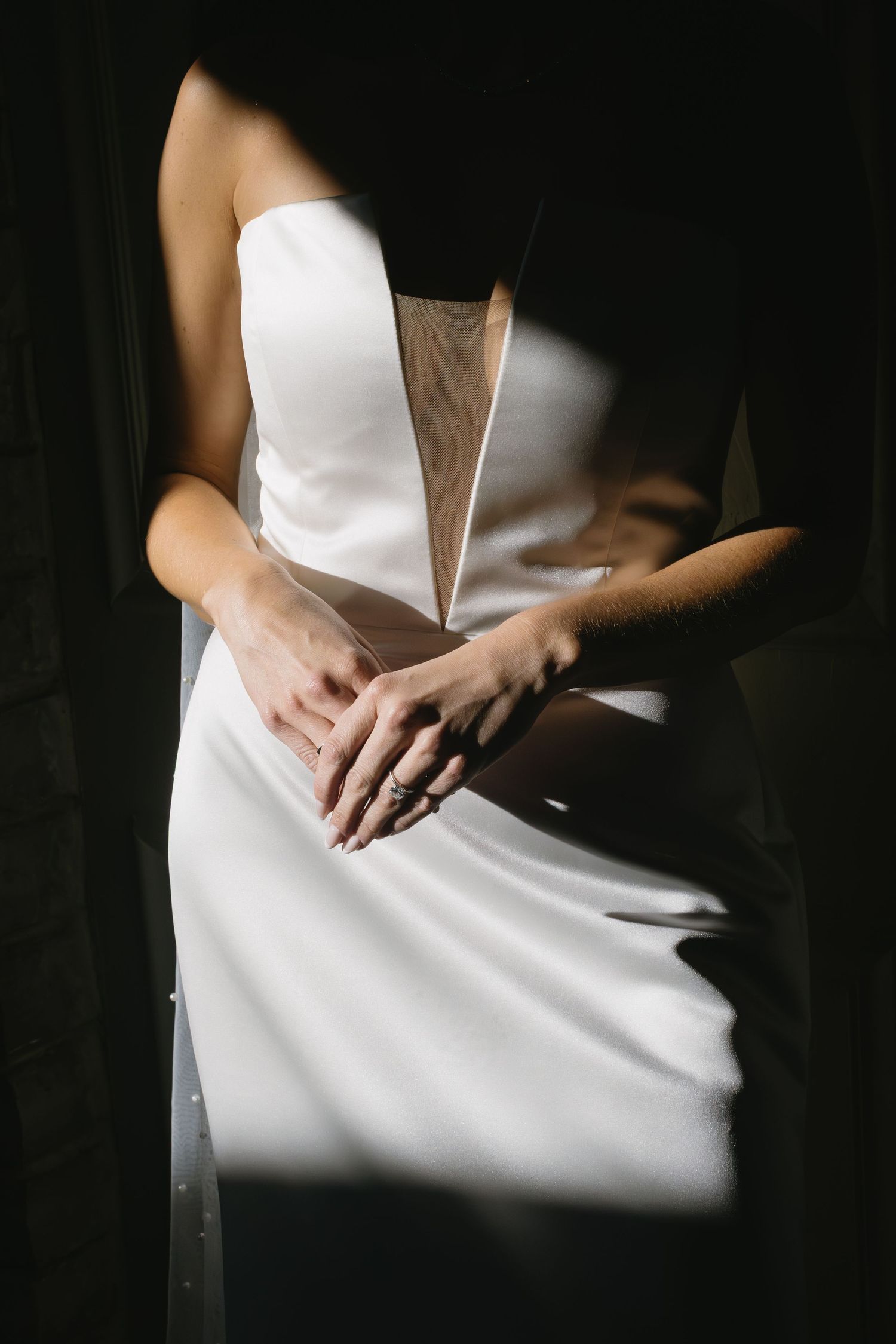 Artistic black and white photo showing details of an elegant white wedding dress.