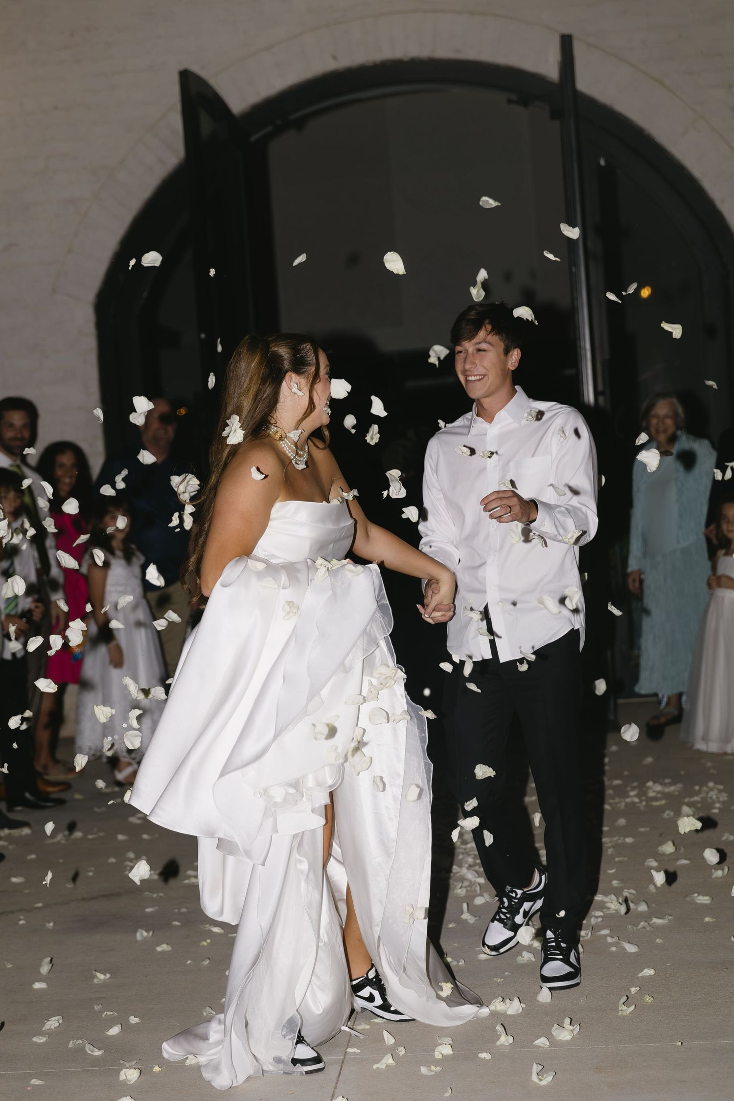 Wedding reception exit with flower petals being tossed as couple dances.