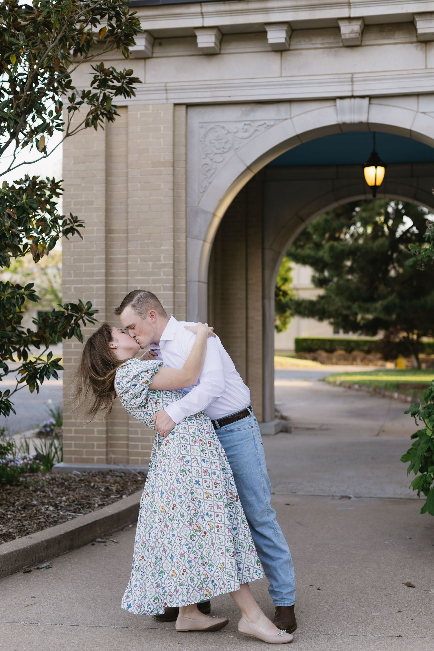 A romantic couple shares tender moments in front of a stone archway during a photo session.