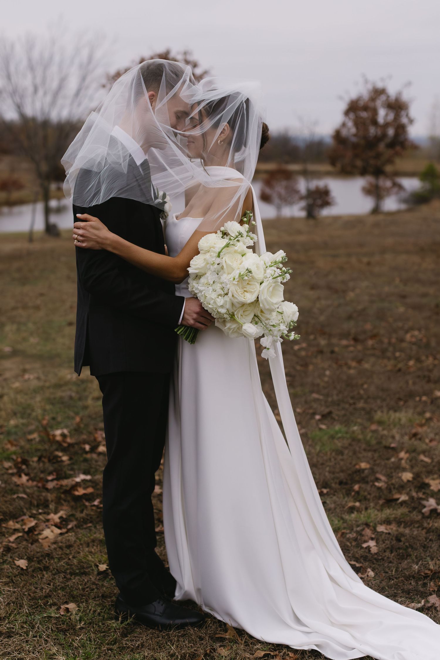 Elegant white wedding bouquet and flowing dress captured in an autumn outdoor setting.