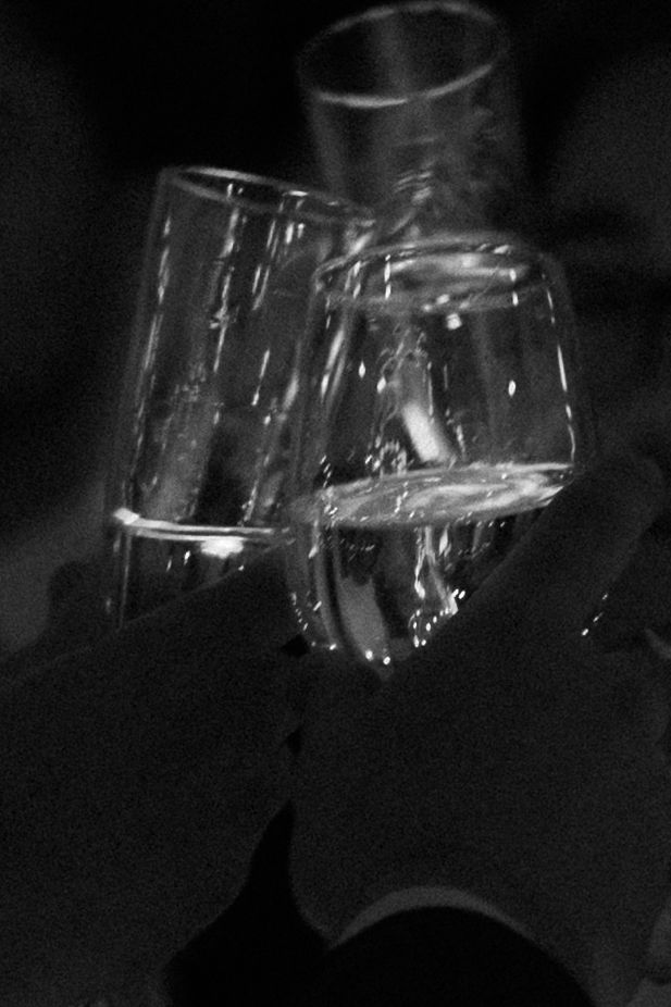 Black and white close-up of champagne glasses clinking in celebration.