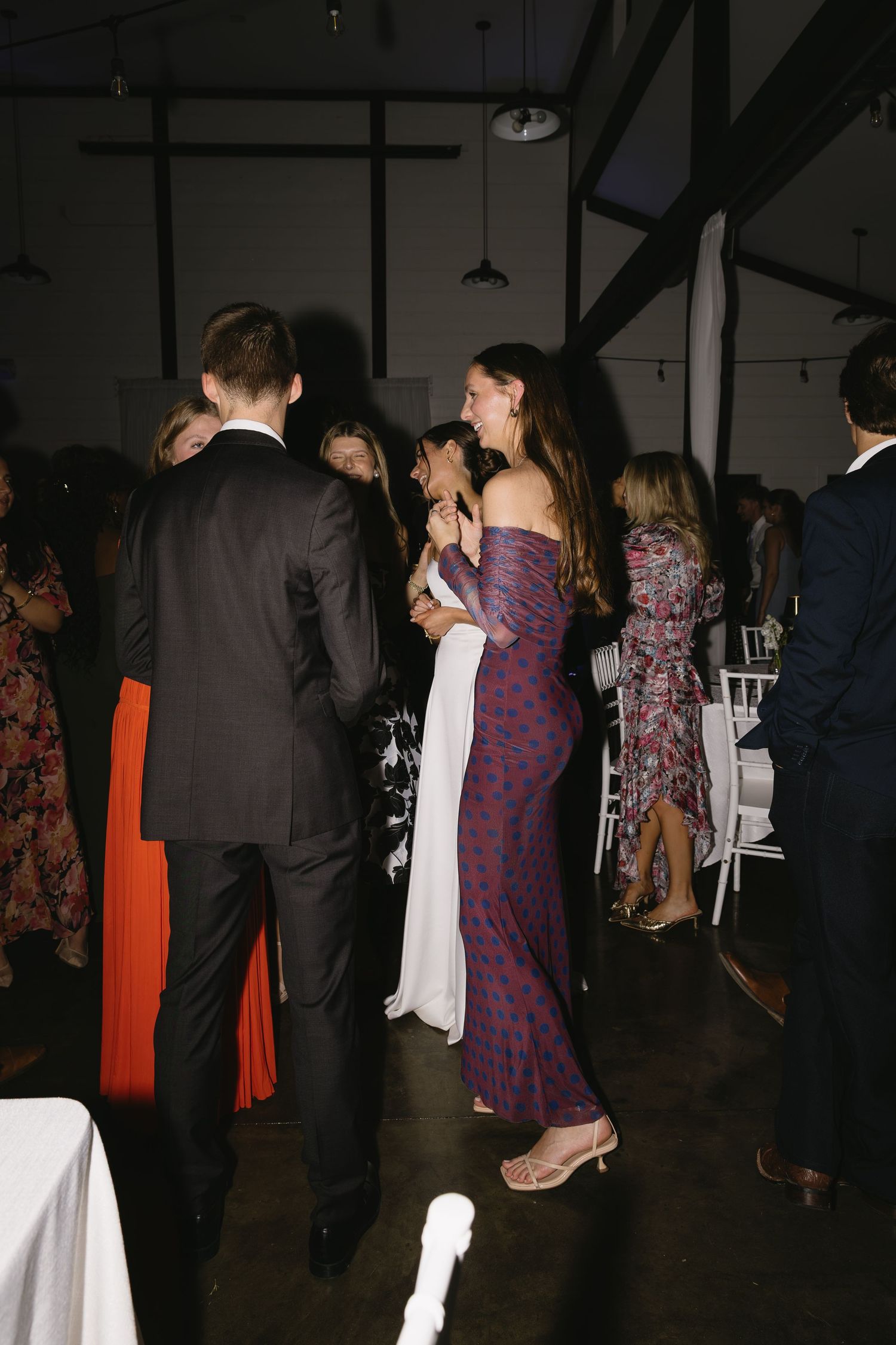 Wedding reception guests mingling and dancing in an industrial-style venue.